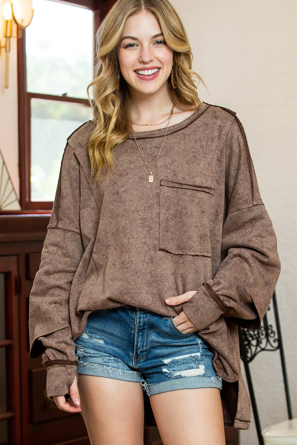 Brown sweatshirt featuring exposed seams, thumbholes, and drop shoulder design, perfect for a relaxed and stylish look.