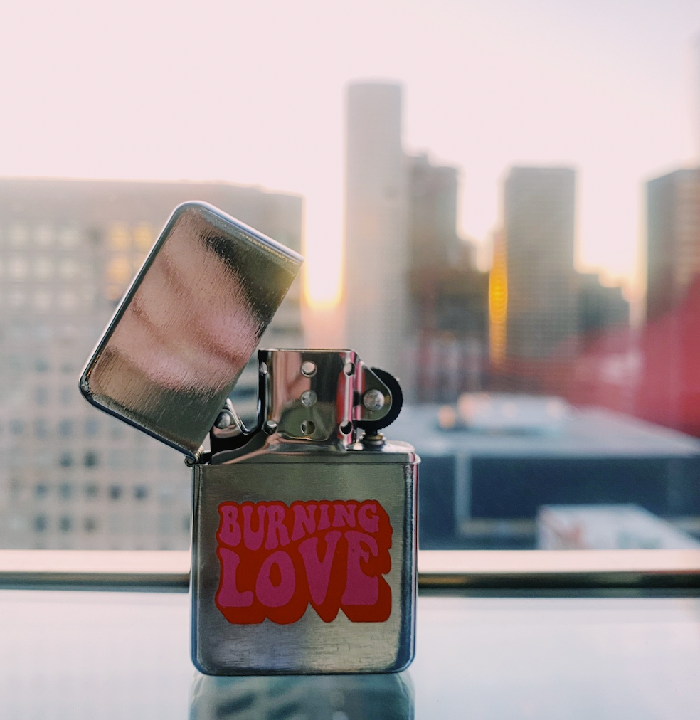 A stylish silver-brushed metal lighter named 'Burning Love', featuring a spring action flip top and compact design, perfect for Elvis fans.