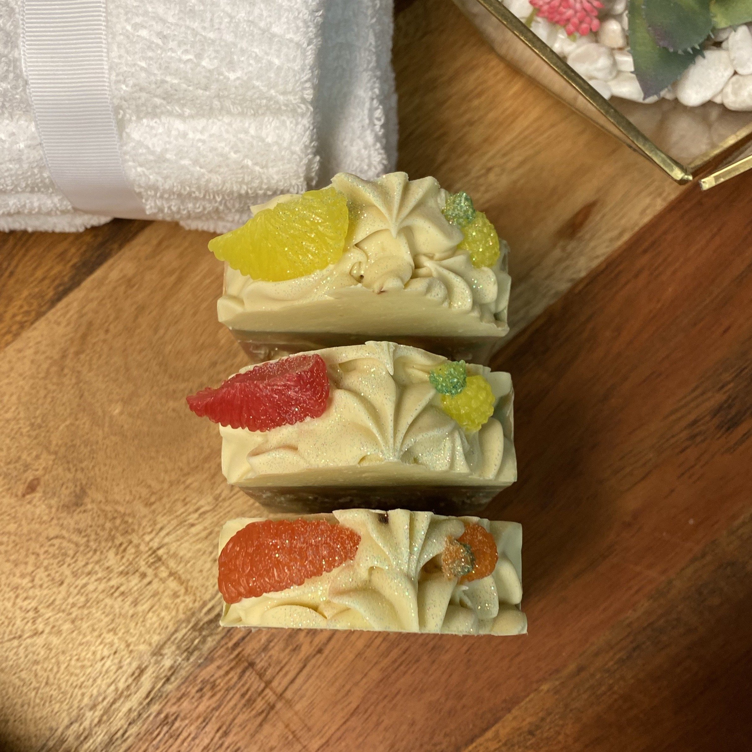 A vibrant bar of Caribbean Soap shaped like tropical fruits, featuring coconut and pineapple scents, with a creamy texture and colorful mica coloring.