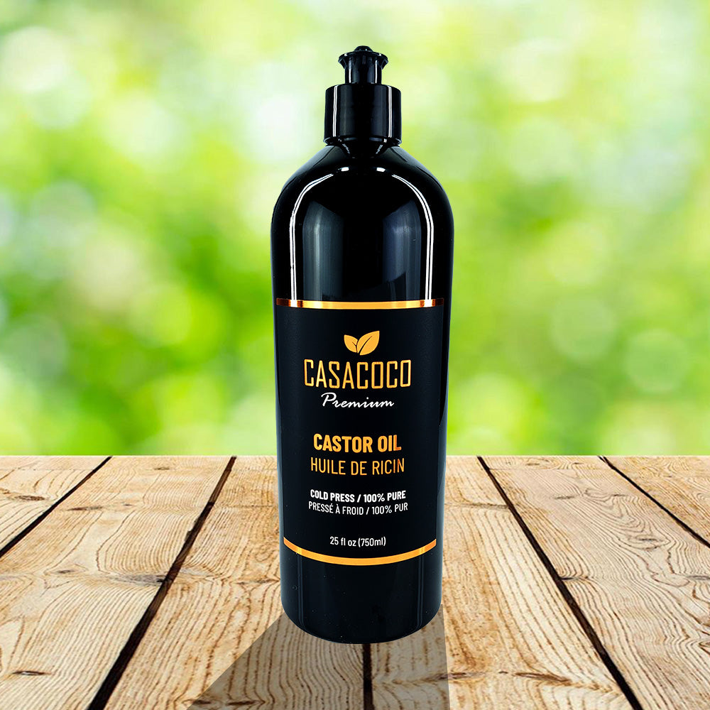 A bottle of 100% pure castor oil with a dropper, surrounded by castor seeds and green leaves, showcasing its natural origins.