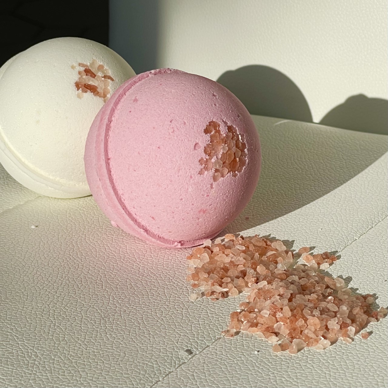 Cherry Blossom and Himalayan Salt Bath Bomb in a pink hue, surrounded by delicate cherry blossoms, showcasing its luxurious and soothing properties.