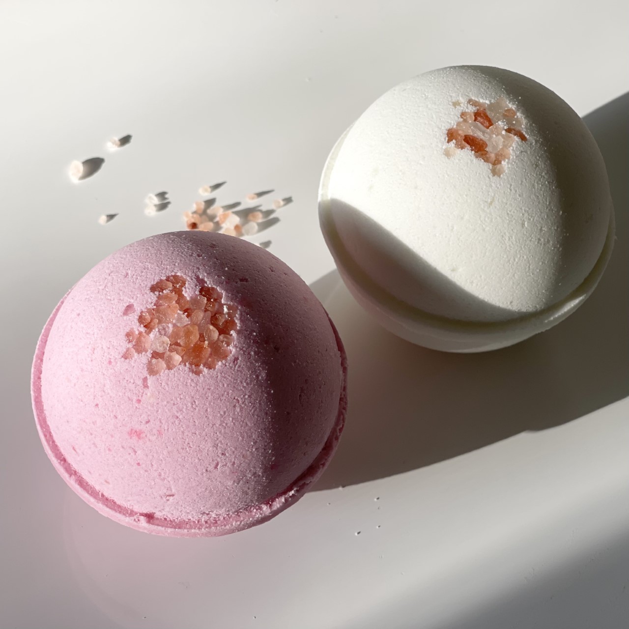 Cherry Blossom and Himalayan Salt Bath Bomb in a pink hue, surrounded by delicate cherry blossoms, showcasing its luxurious and soothing properties.