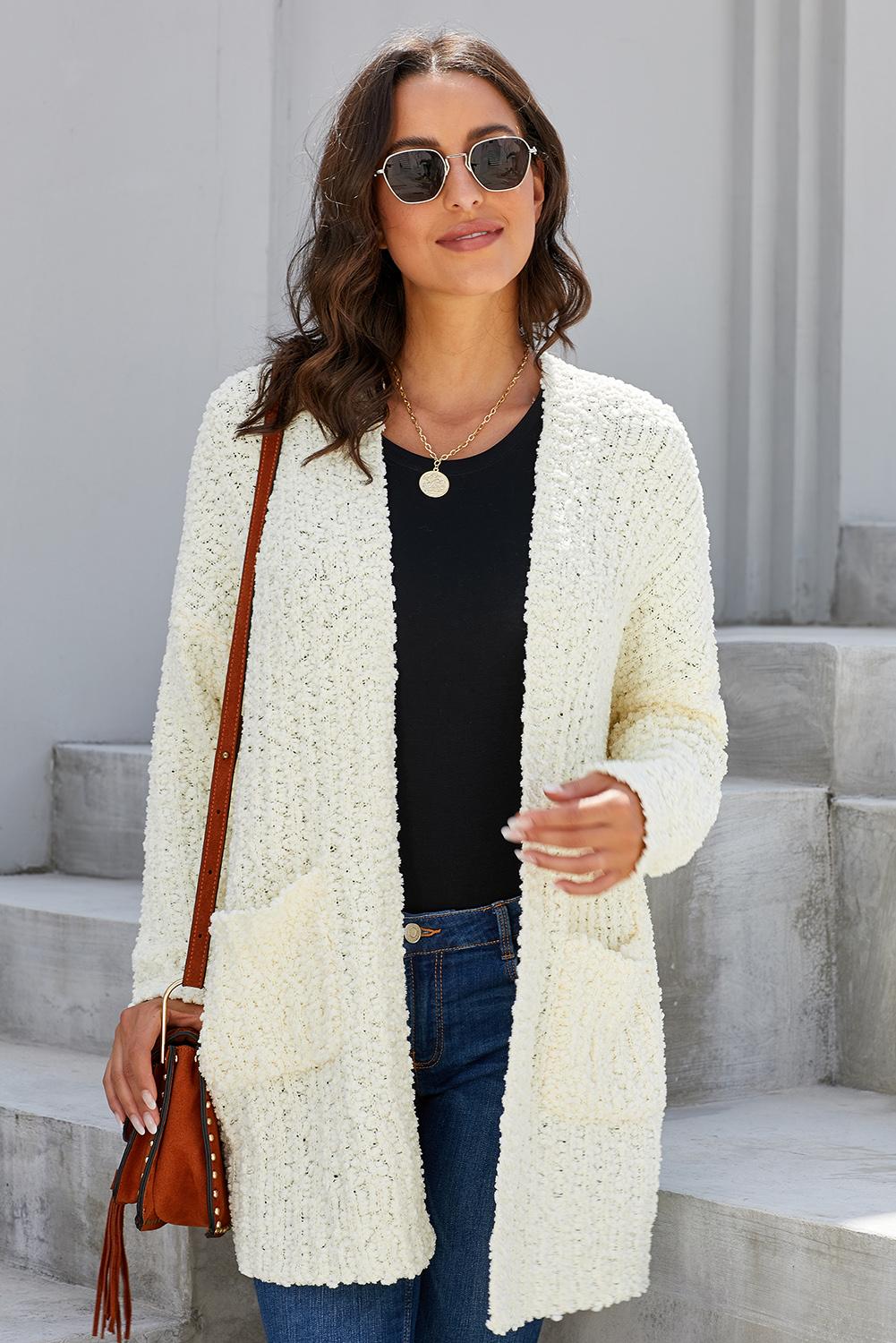 A soft and luxurious Creamy Pebble Beach Textured Cardigan with an open front and two pockets, showcasing its beautiful color and textured fabric.