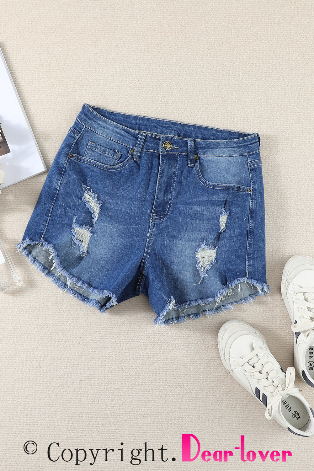 A pair of dark blue frayed hem denim shorts displayed on a white background, showcasing the stylish distressed design and pockets.