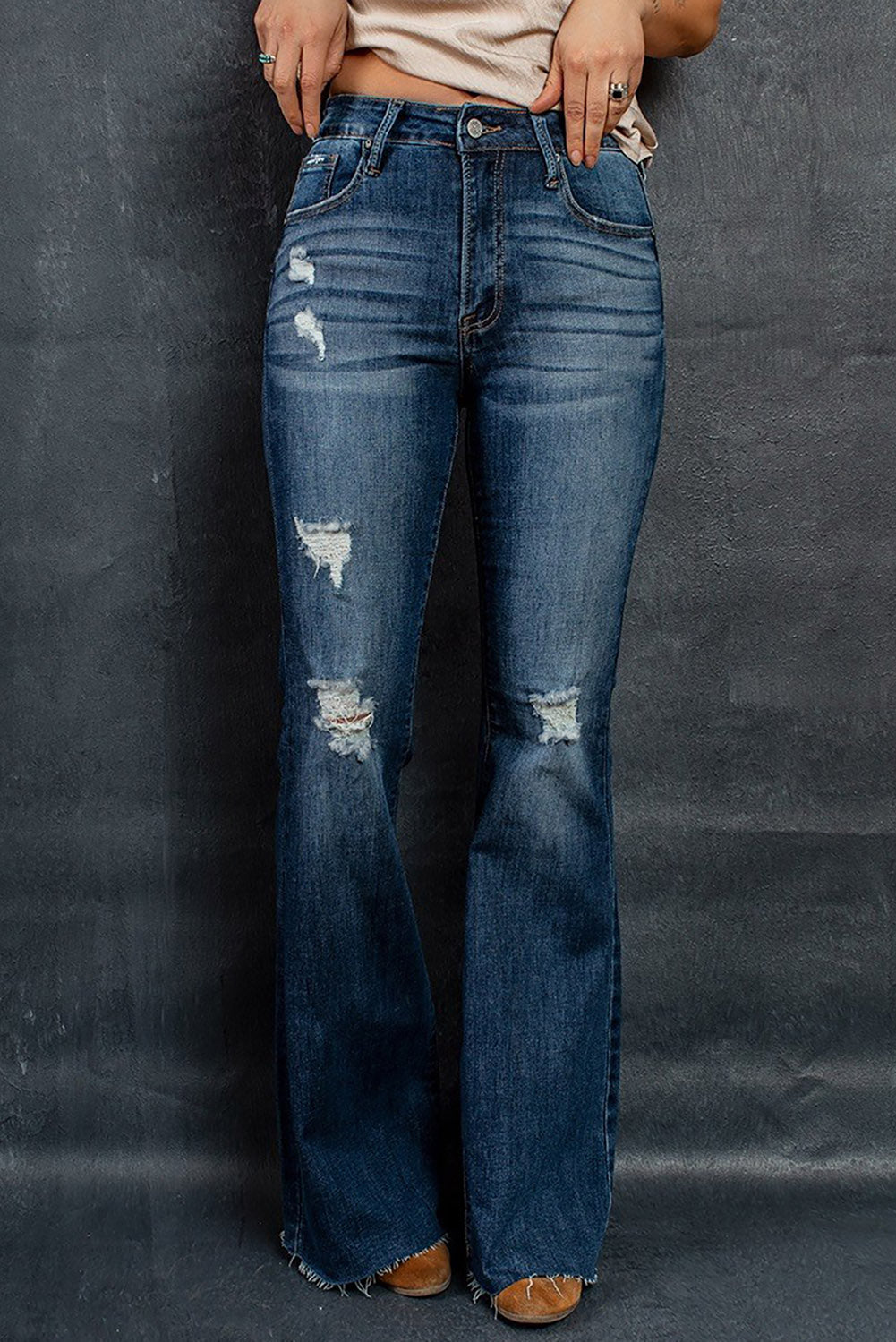 A pair of dark wash mid rise flare jeans featuring a trendy ripped design and raw hem detail, perfect for stylish casual wear.