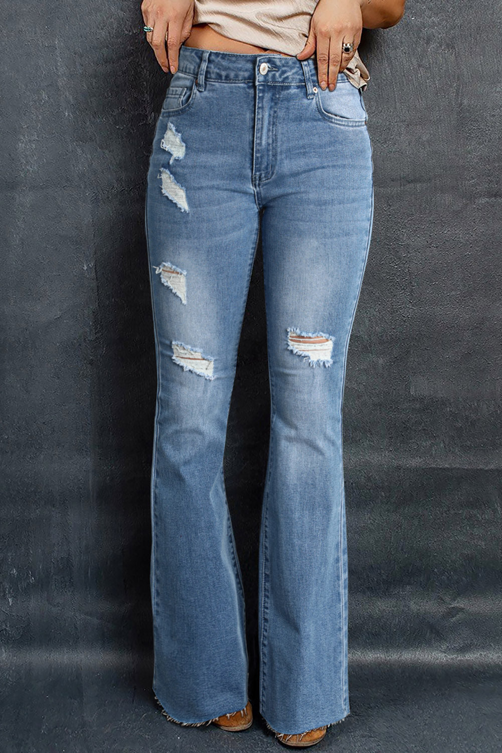 A pair of dark wash mid rise flare jeans featuring a trendy ripped design and raw hem detail, perfect for stylish casual wear.