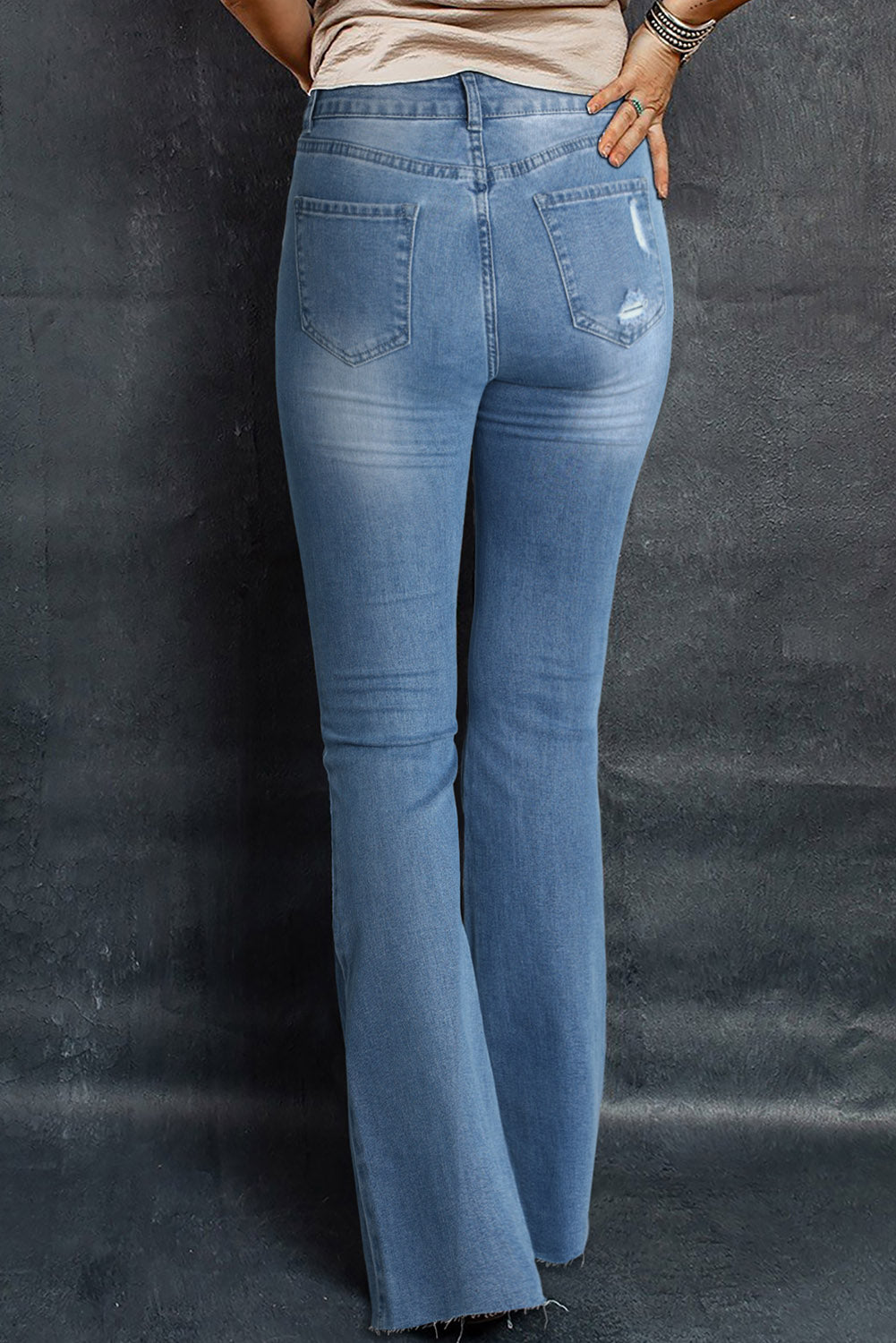 A pair of dark wash mid rise flare jeans featuring a trendy ripped design and raw hem detail, perfect for stylish casual wear.