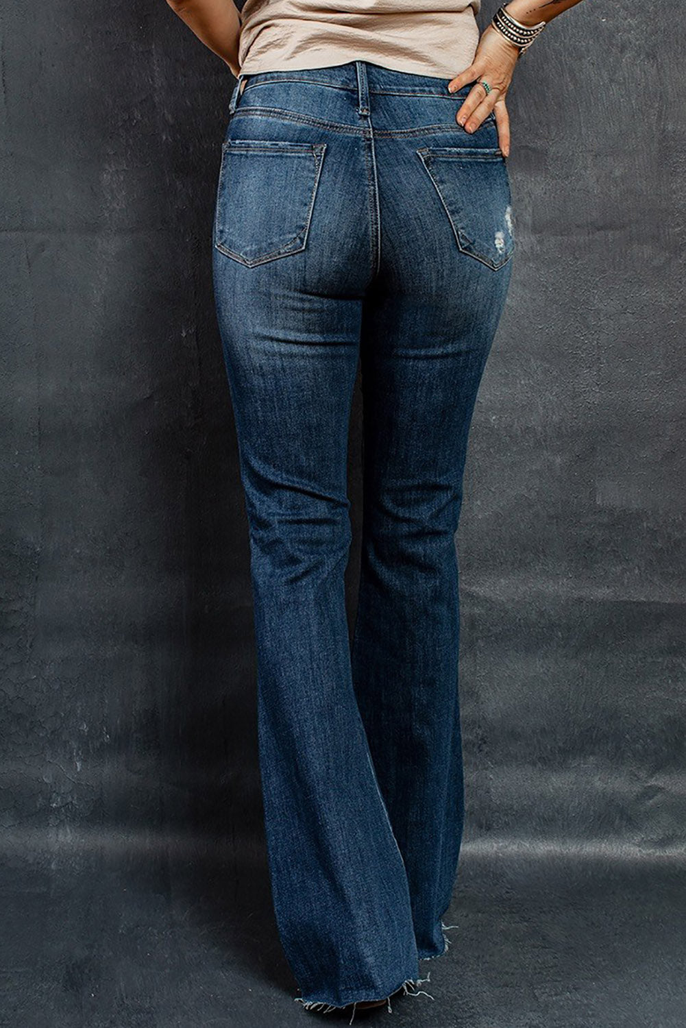 A pair of dark wash mid rise flare jeans featuring a trendy ripped design and raw hem detail, perfect for stylish casual wear.