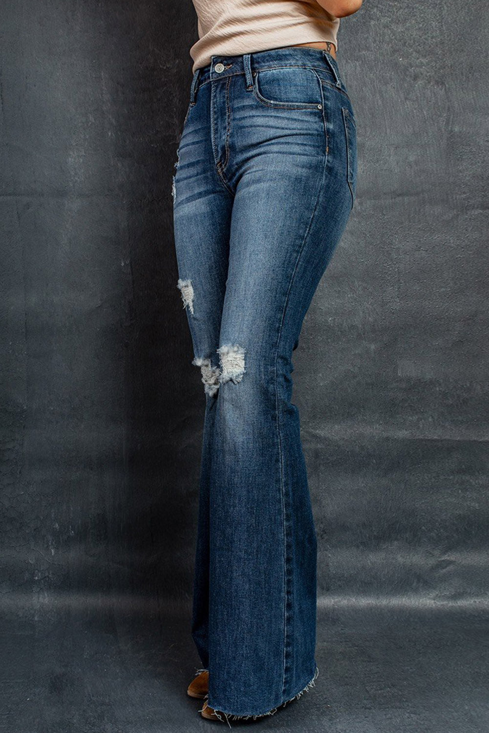 A pair of dark wash mid rise flare jeans featuring a trendy ripped design and raw hem detail, perfect for stylish casual wear.