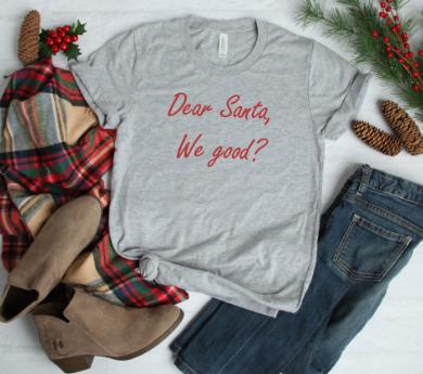 A soft, unisex graphic tee featuring the text 'Dear Santa We Good' in festive colors, available in multiple options.