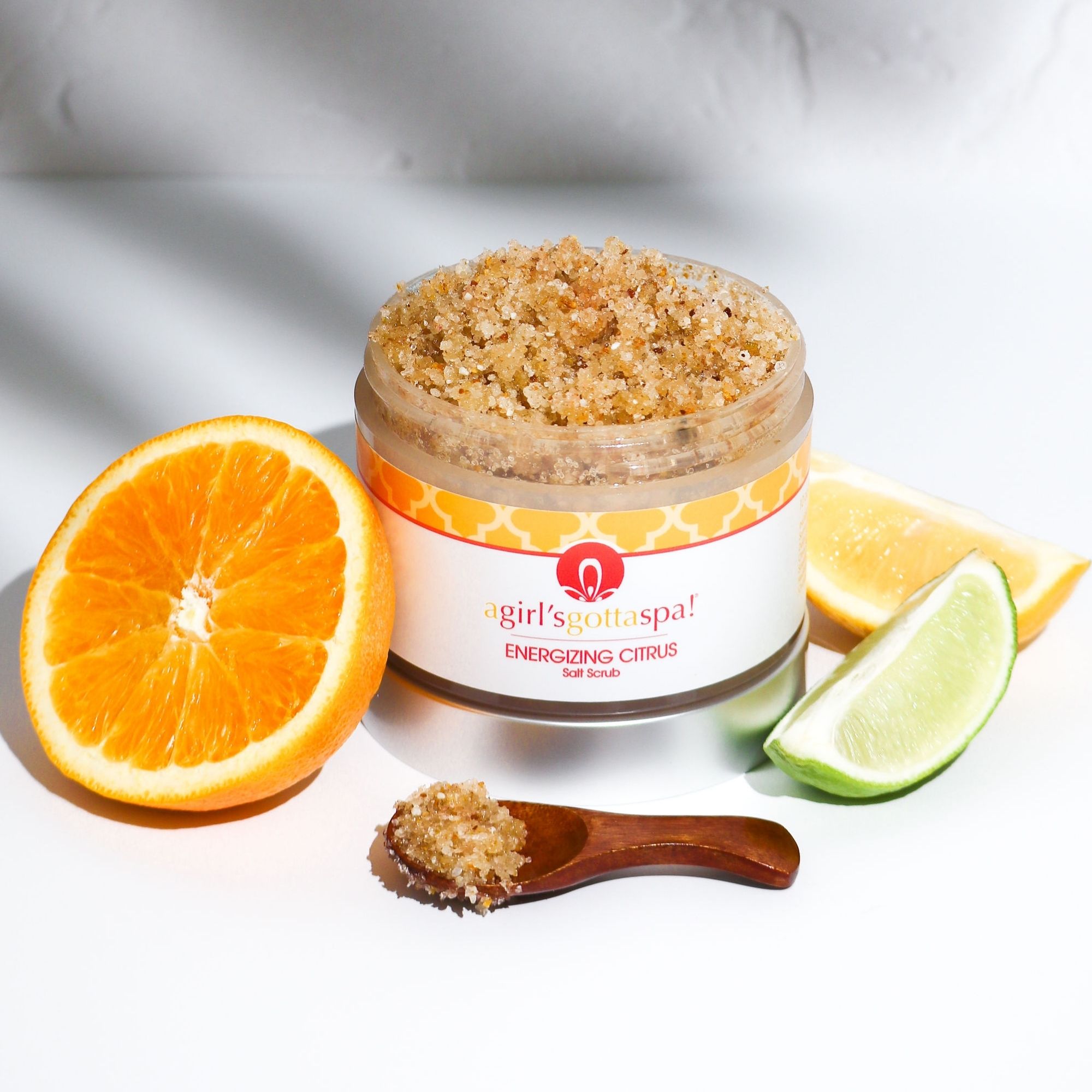 Energizing Citrus Salt Body Scrub in a jar with a wooden spoon, showcasing its vibrant texture and citrus scent.