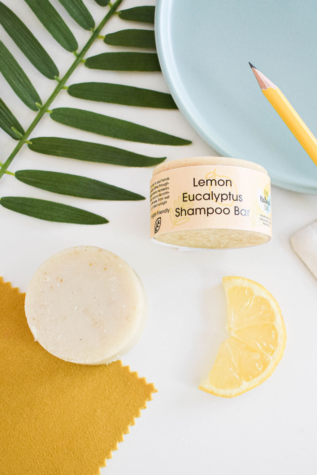 Eucalyptus Lemon Shampoo Bar, a plastic-free solid shampoo with natural ingredients, displayed on a wooden surface with eucalyptus leaves.