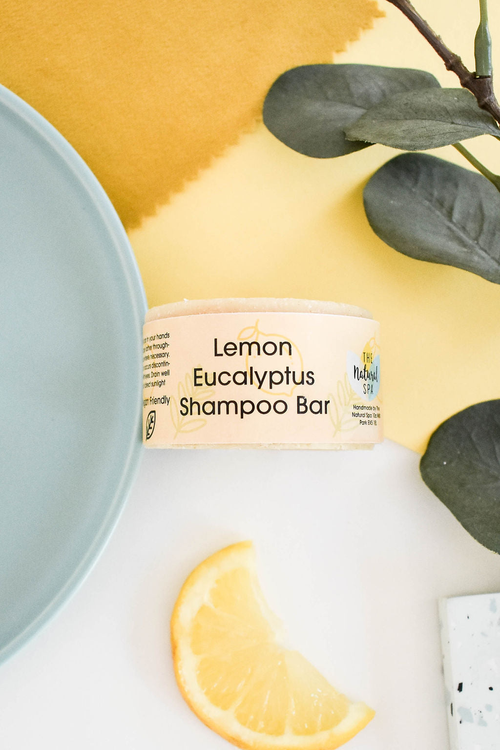 Eucalyptus Lemon Shampoo Bar, a plastic-free solid shampoo with natural ingredients, displayed on a wooden surface with eucalyptus leaves.