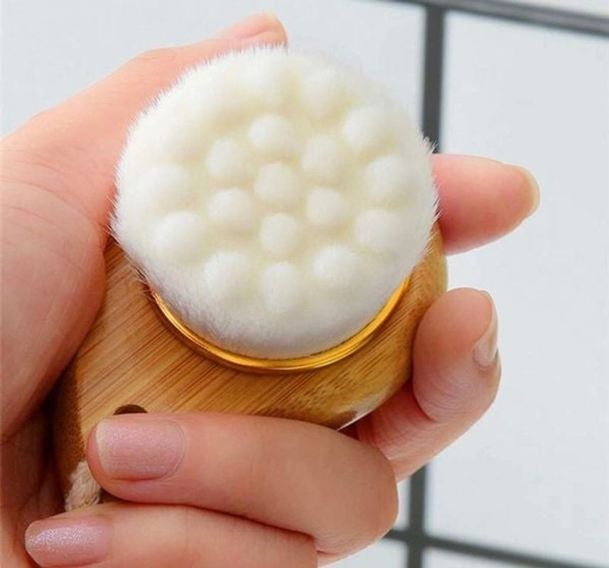 Facial brush with a bamboo handle and soft bristles, ideal for gentle exfoliation and cleansing of the face.