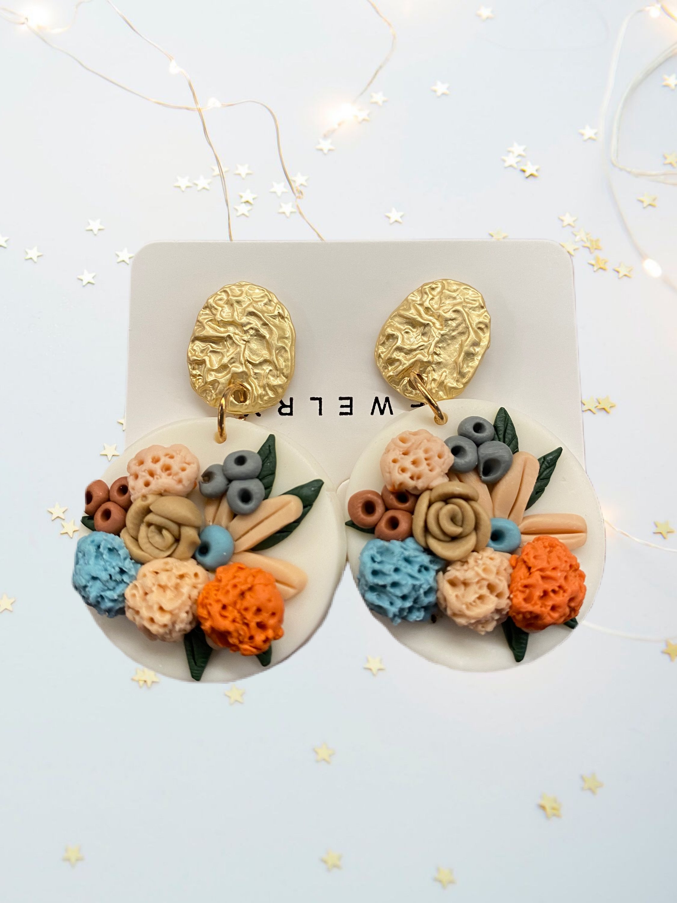 A pair of beautifully handcrafted floral clay earrings featuring intricate floral designs in vibrant colors.