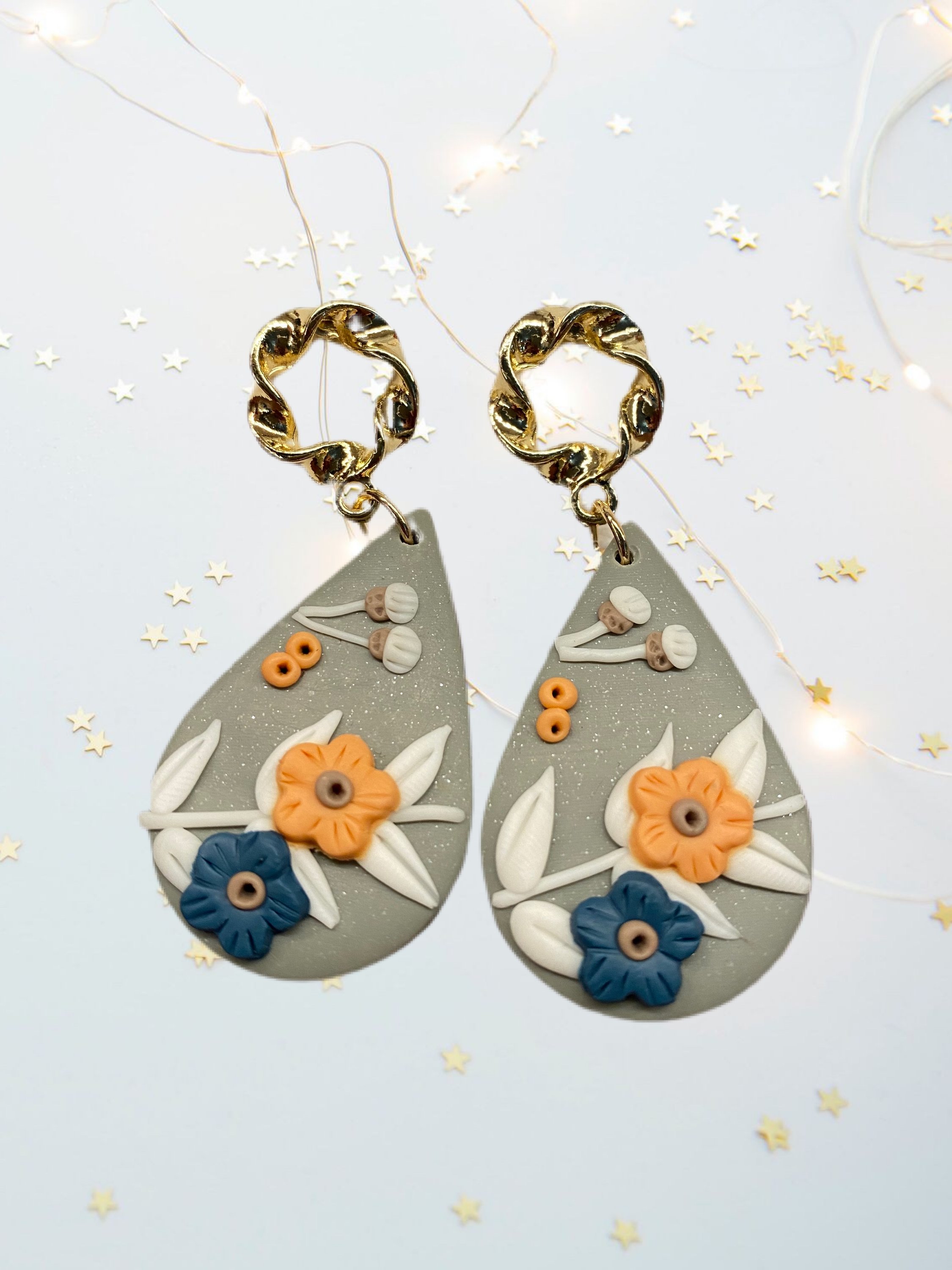 A pair of beautifully handcrafted floral clay earrings featuring intricate floral designs in vibrant colors.