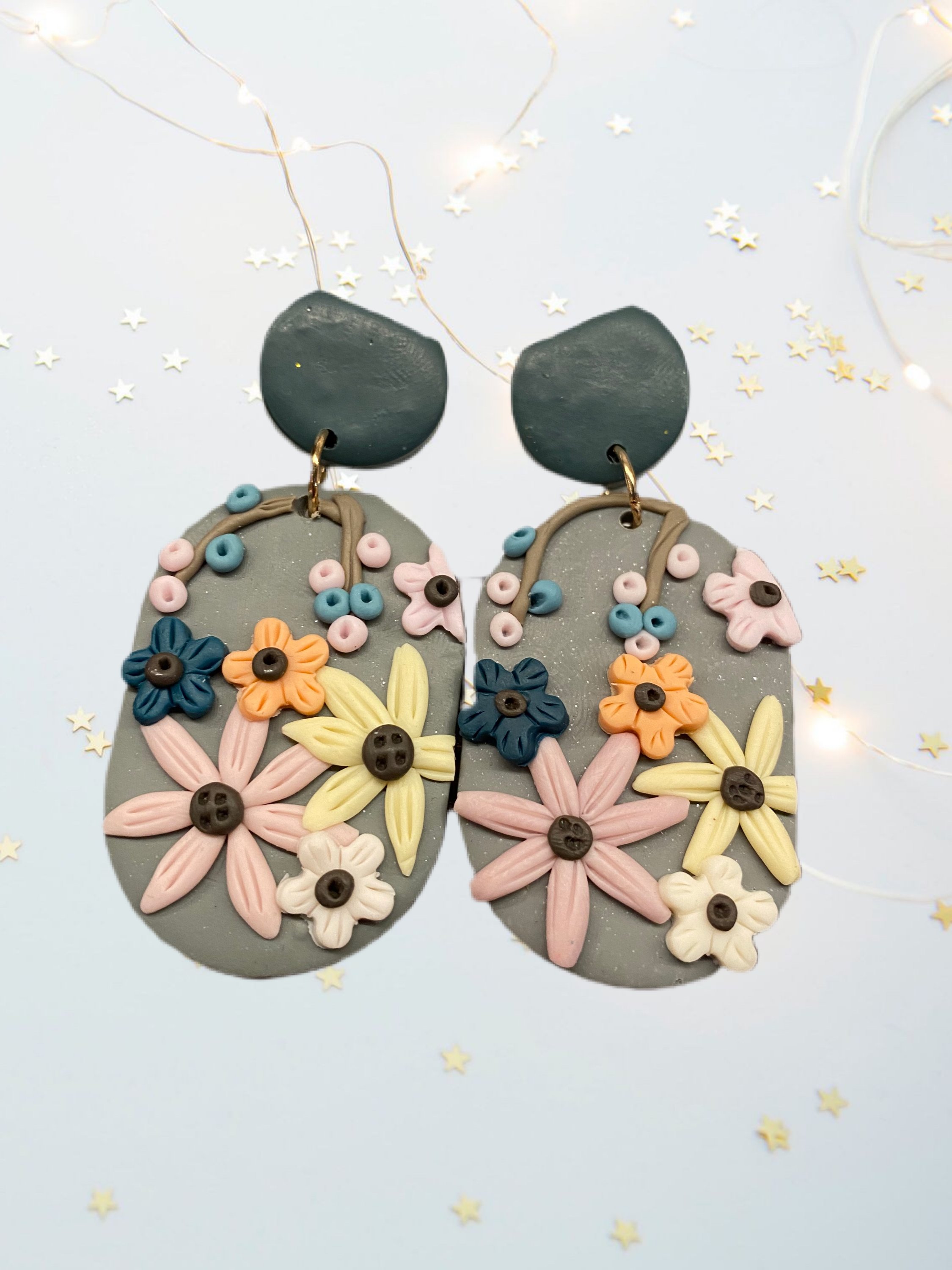 A pair of beautifully handcrafted floral clay earrings featuring intricate floral designs in vibrant colors.