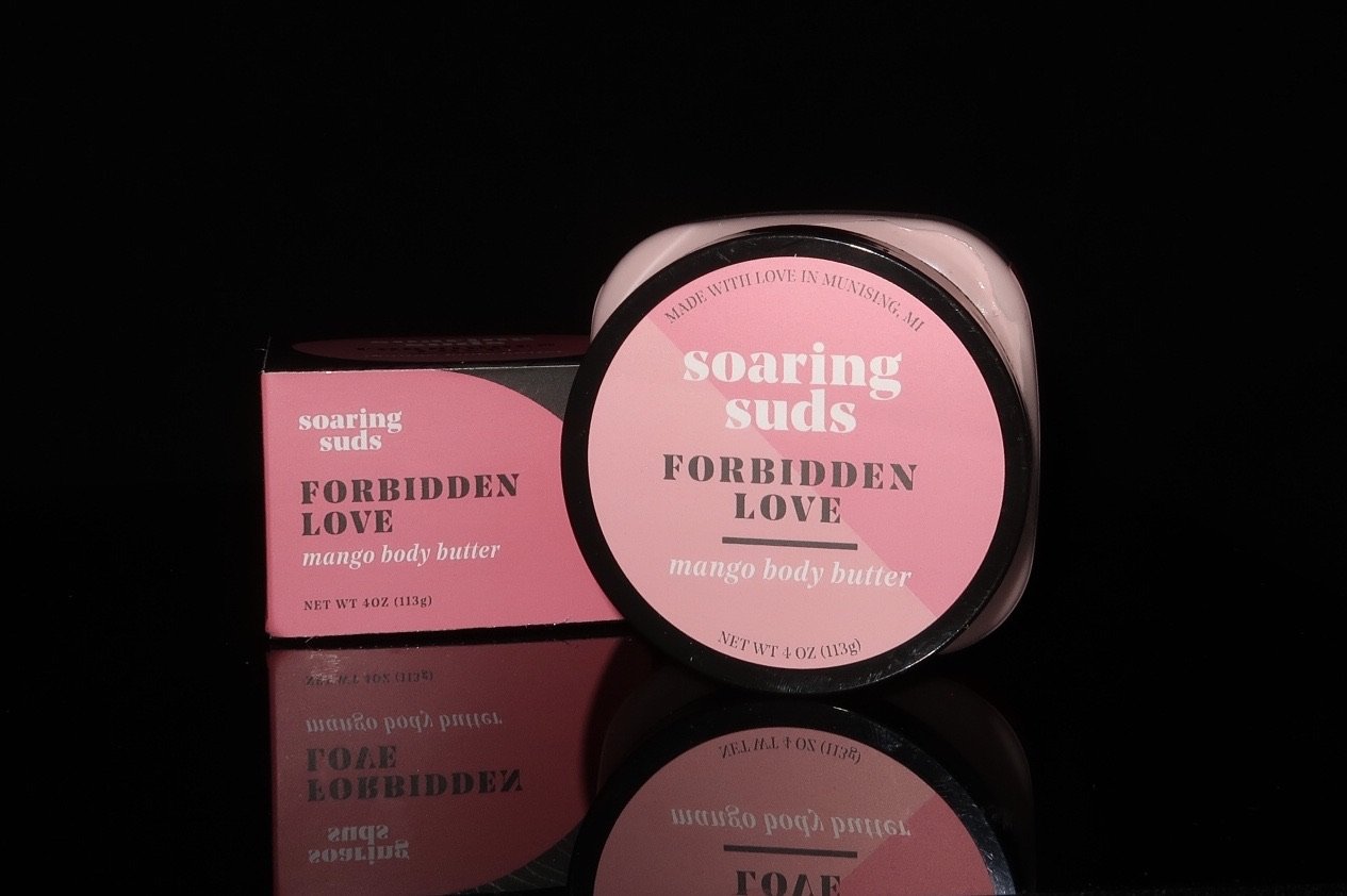 A 4 oz jar of Forbidden Love Mango Body Butter with a bright citrus and rose scent, showcasing its creamy texture and natural ingredients.