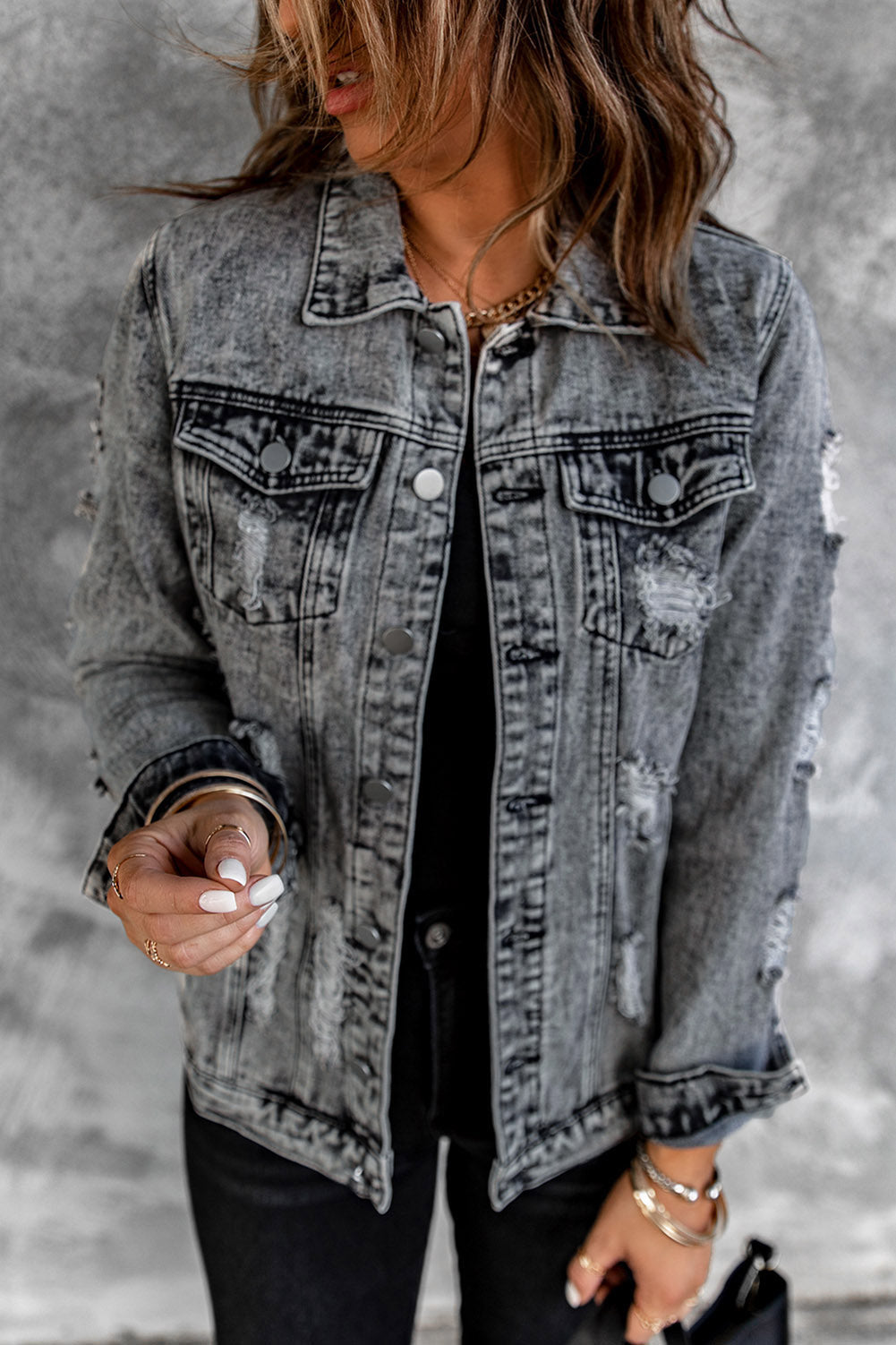 Gray distressed denim jacket featuring buttoned closure, turn down collar, and long sleeves, perfect for stylish layering.