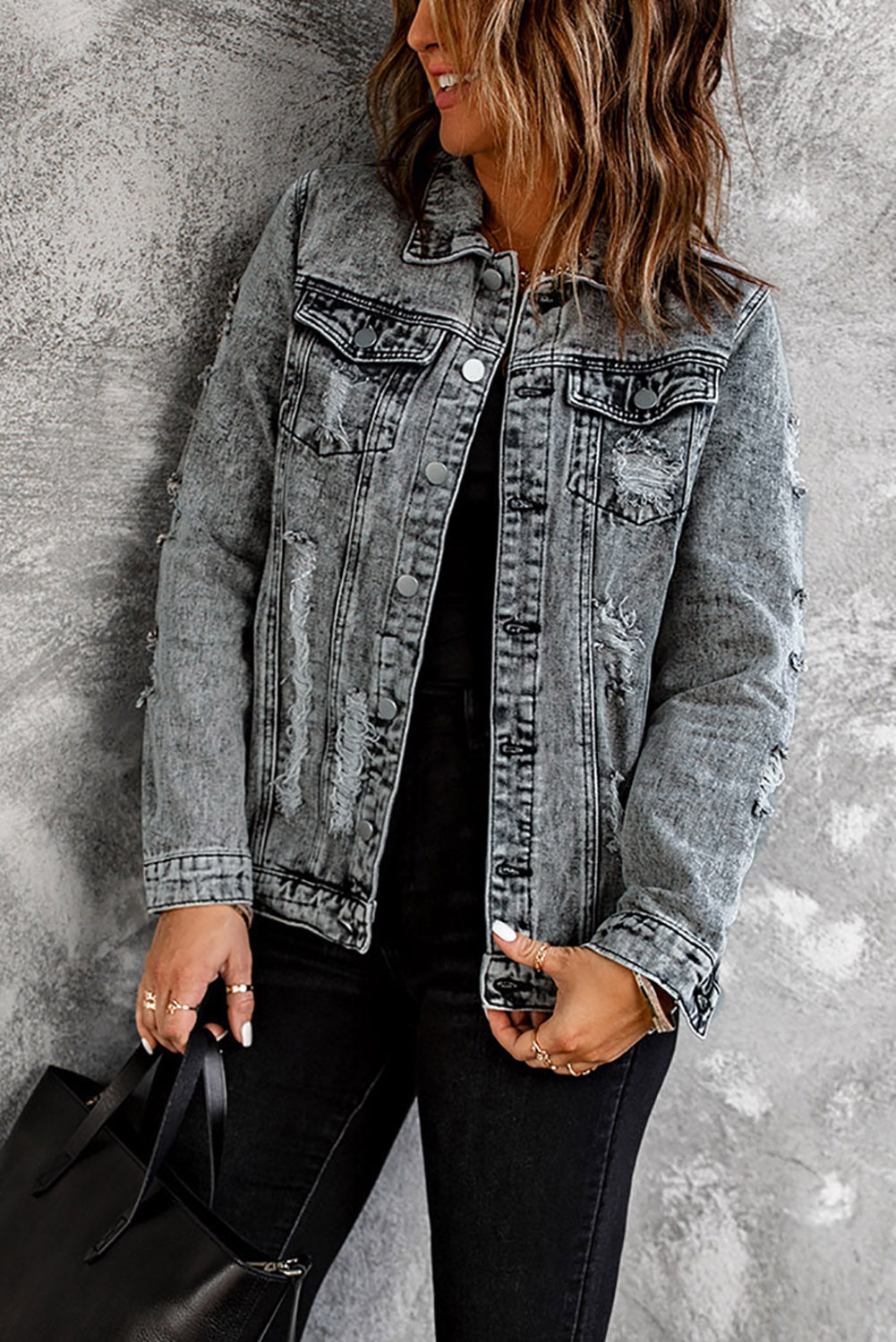 Gray distressed denim jacket featuring buttoned closure, turn down collar, and long sleeves, perfect for stylish layering.