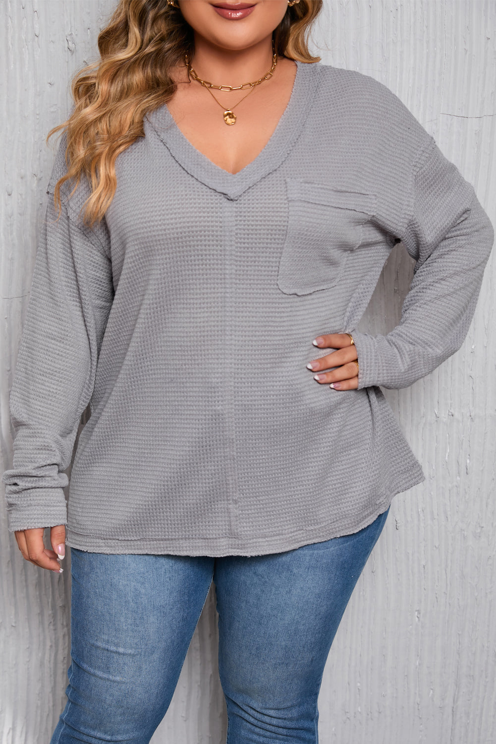 Gray Plus Size V Neck Raw Edge Long Sleeve Top displayed on a mannequin, showcasing its relaxed fit and trendy design.