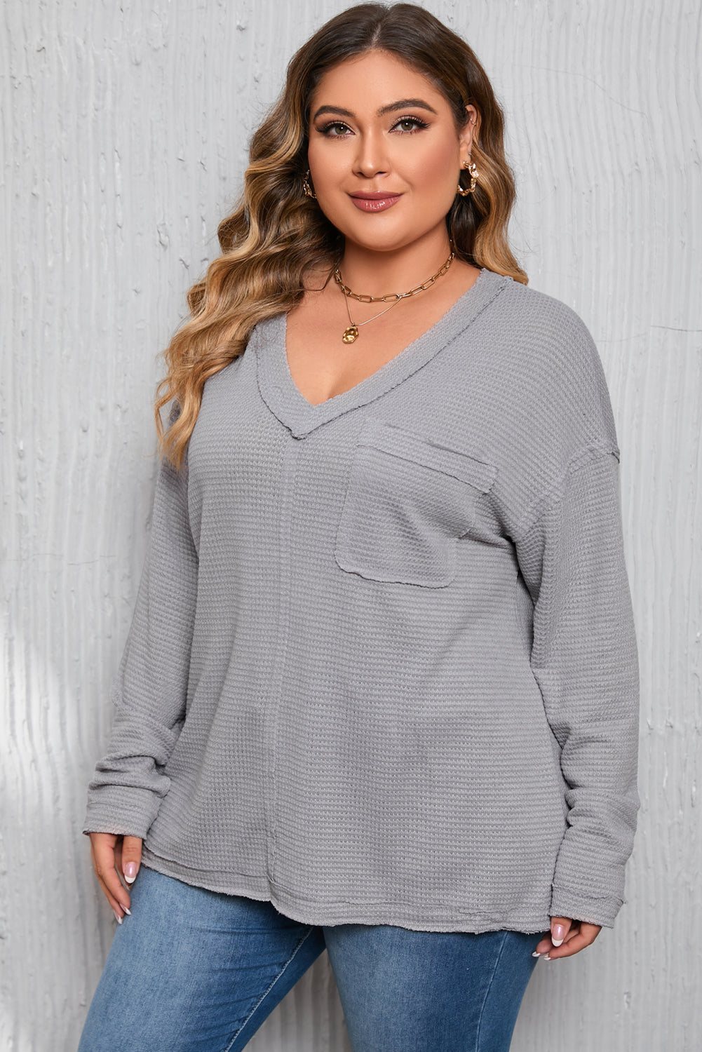 Gray Plus Size V Neck Raw Edge Long Sleeve Top displayed on a mannequin, showcasing its relaxed fit and trendy design.