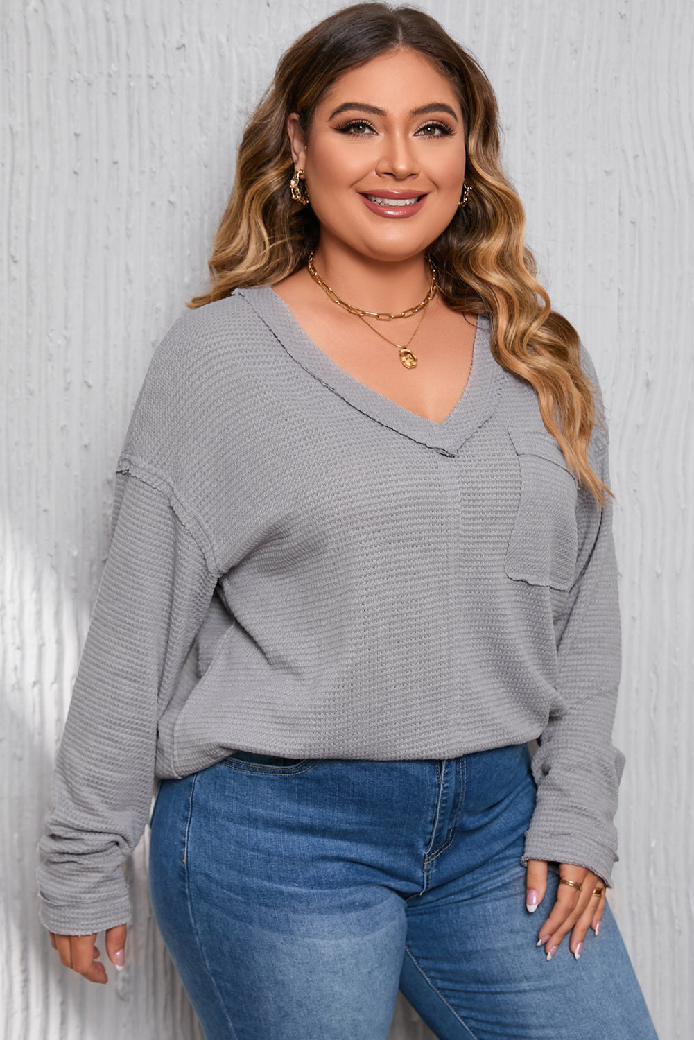 Gray Plus Size V Neck Raw Edge Long Sleeve Top displayed on a mannequin, showcasing its relaxed fit and trendy design.