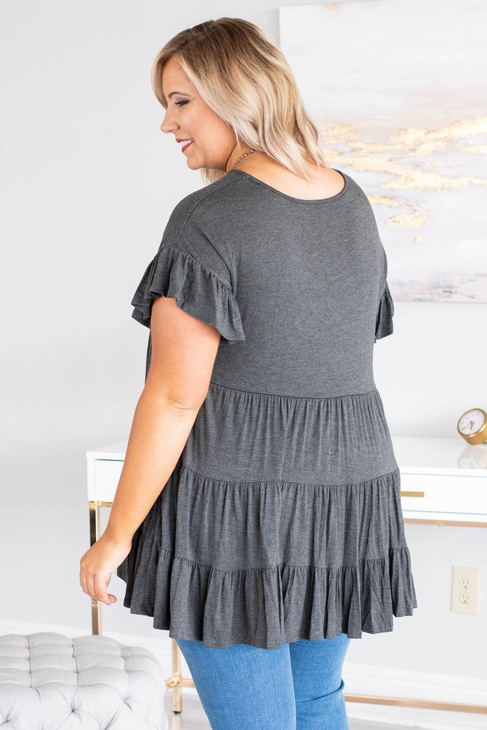 Gray tiered ruffled short sleeve plus size blouse displayed on a mannequin, showcasing its elegant design and comfortable fit.