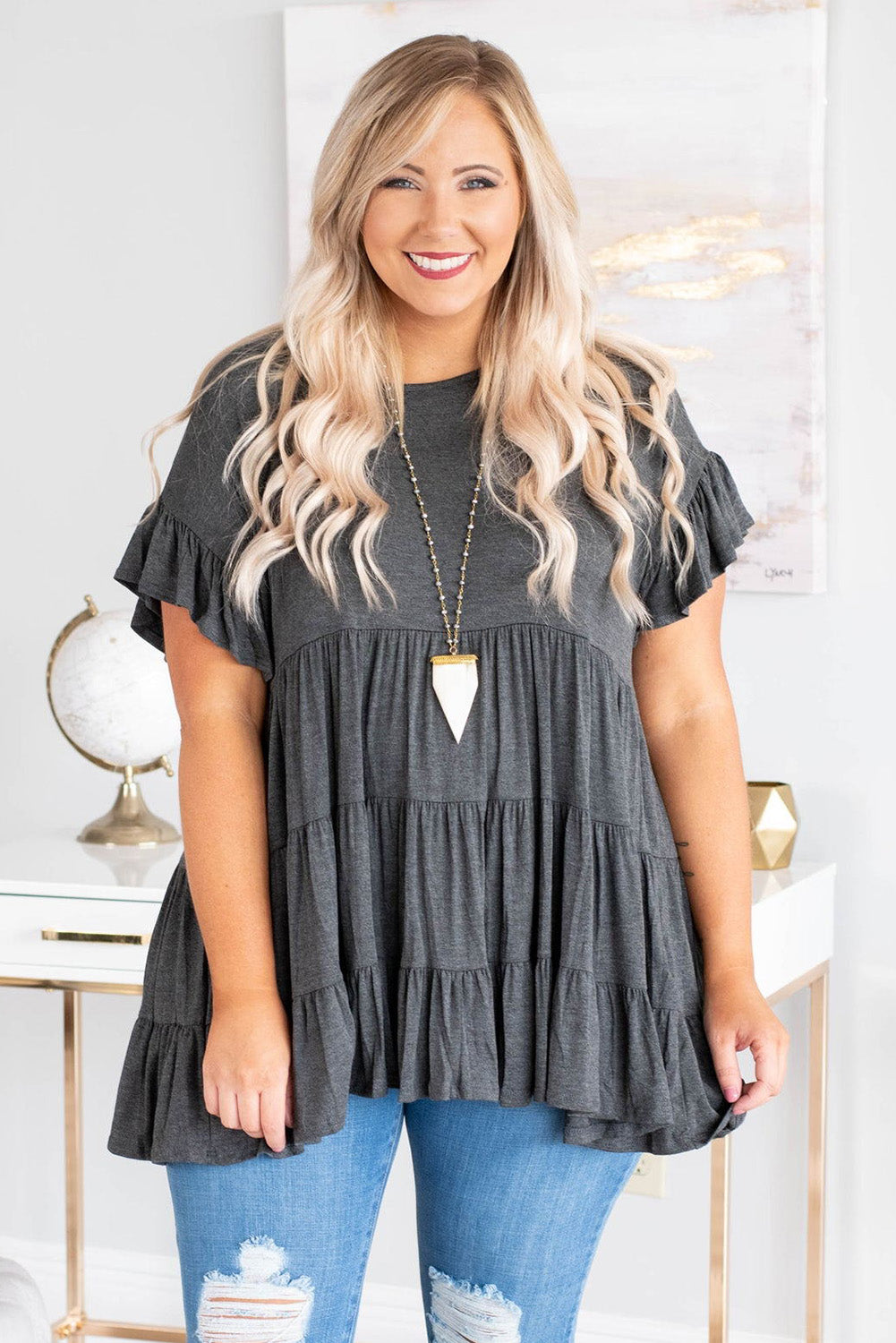 Gray tiered ruffled short sleeve plus size blouse displayed on a mannequin, showcasing its elegant design and comfortable fit.