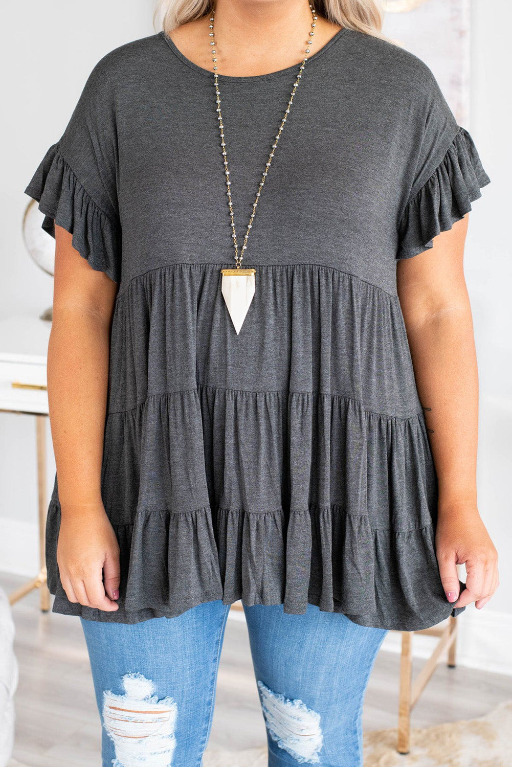 Gray tiered ruffled short sleeve plus size blouse displayed on a mannequin, showcasing its elegant design and comfortable fit.