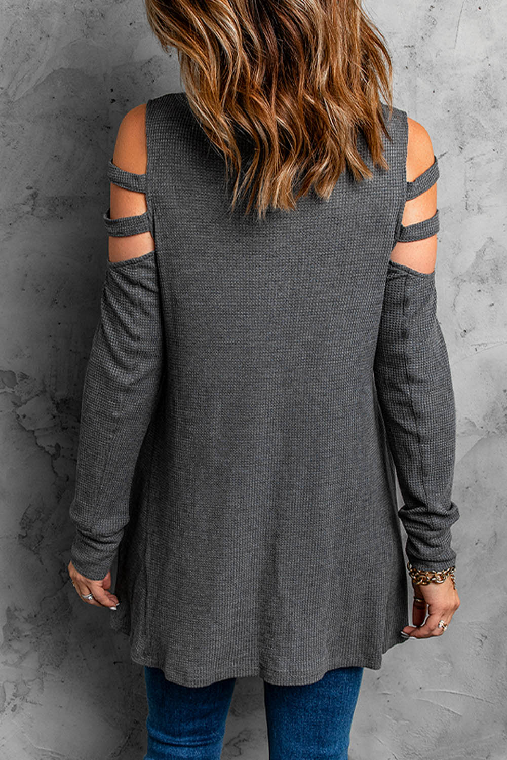 Gray long sleeve top with zip neck and cut-out design, featuring a textured waffle knit fabric and a loose fit with a ruffled hemline.