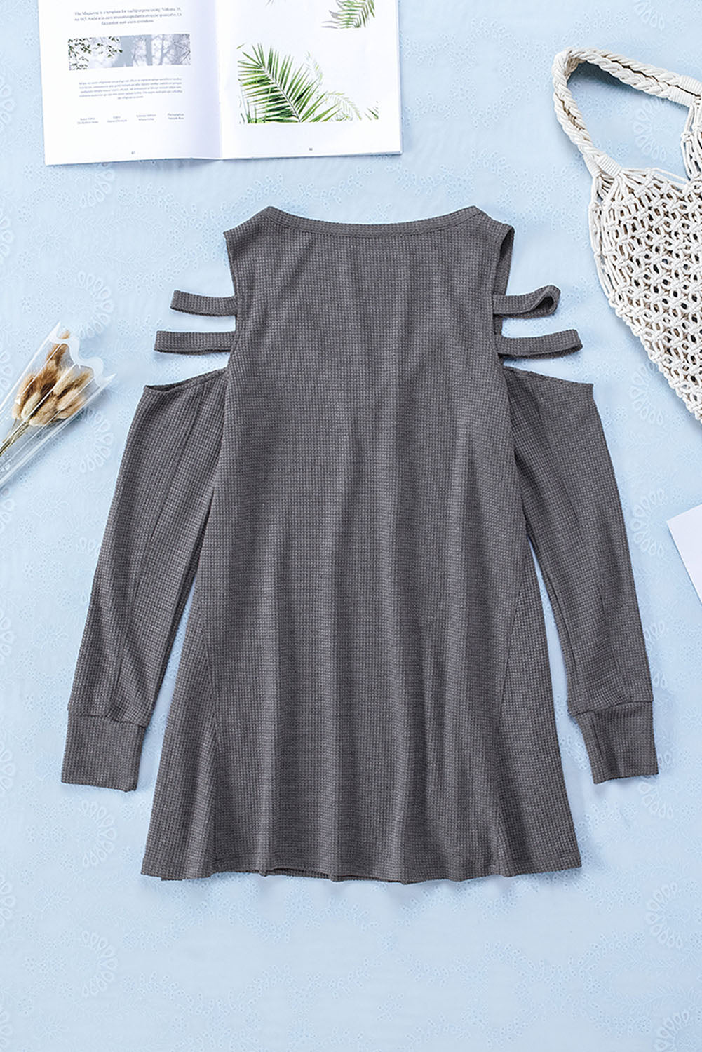 Gray long sleeve top with zip neck and cut-out design, featuring a textured waffle knit fabric and a loose fit with a ruffled hemline.