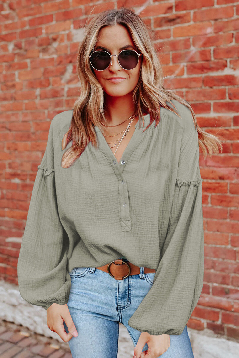 A stylish green casual top featuring balloon sleeves, a split neckline, and snap button closures, perfect for a chic and comfortable look.