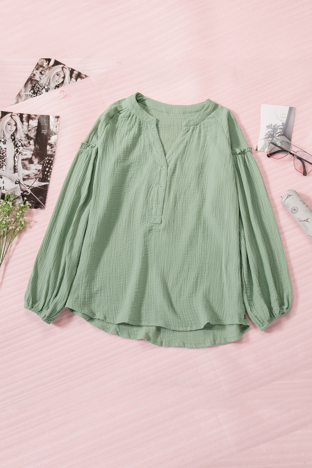 A stylish green casual top featuring balloon sleeves, a split neckline, and snap button closures, perfect for a chic and comfortable look.