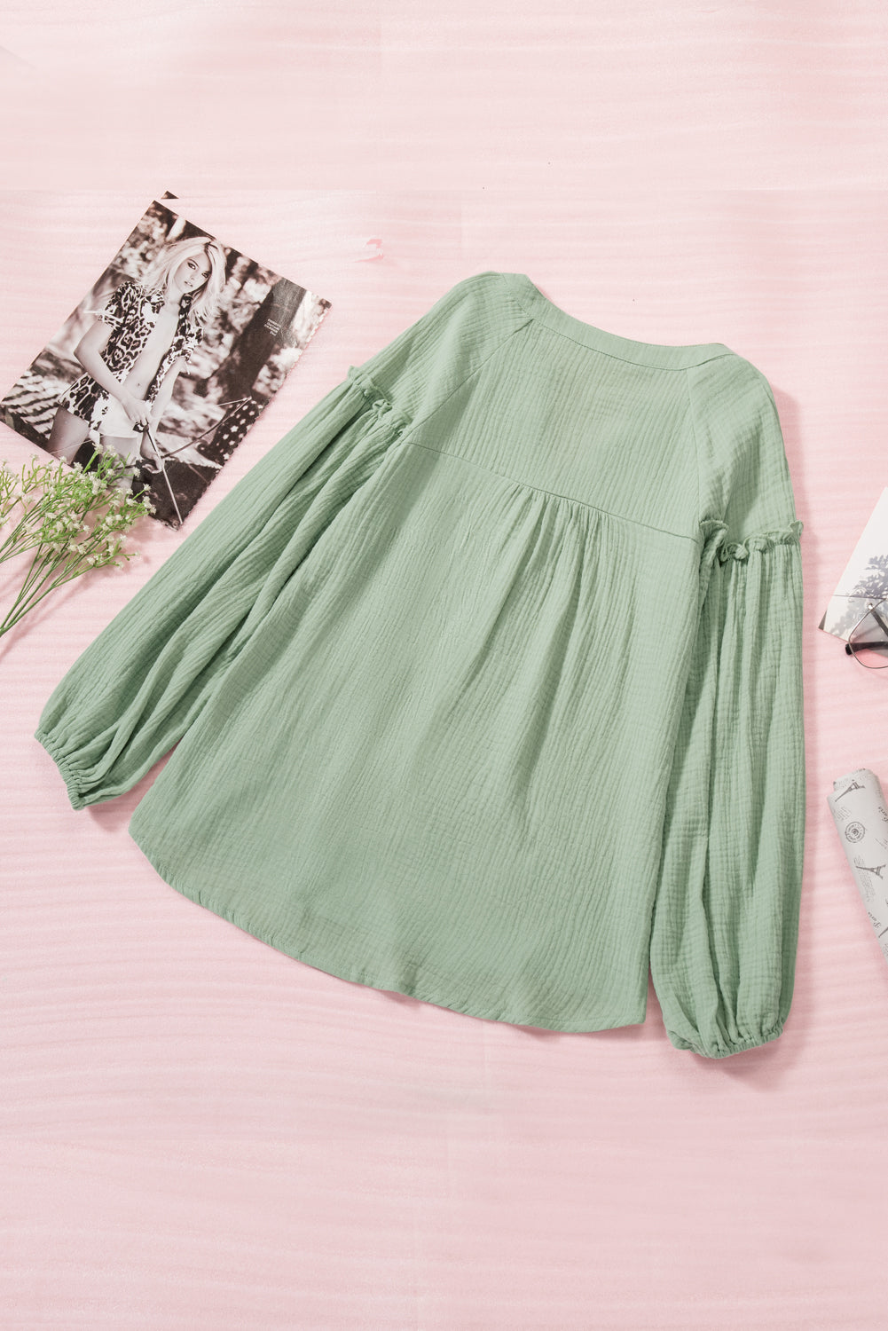 A stylish green casual top featuring balloon sleeves, a split neckline, and snap button closures, perfect for a chic and comfortable look.