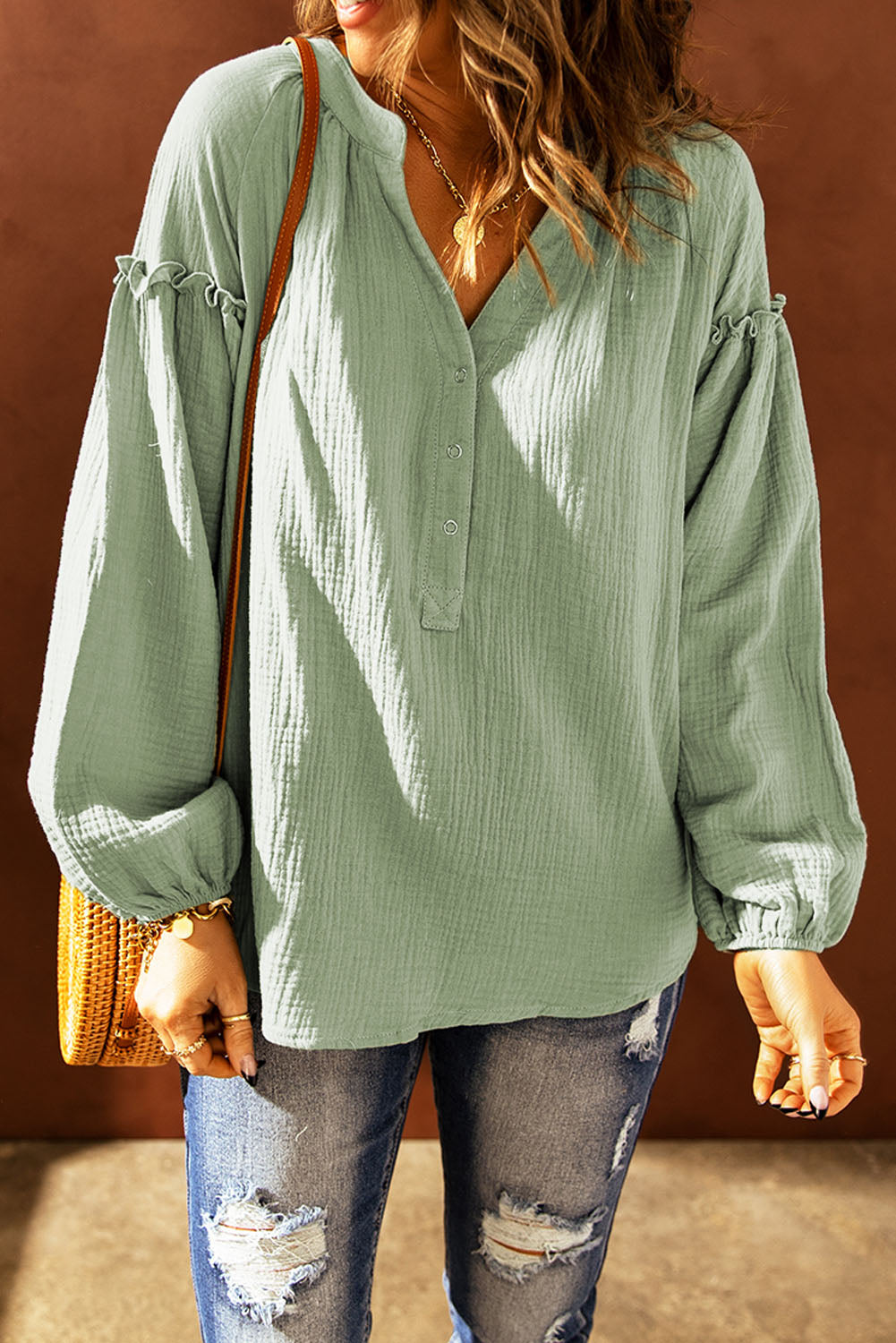 A stylish green casual top featuring balloon sleeves, a split neckline, and snap button closures, perfect for a chic and comfortable look.