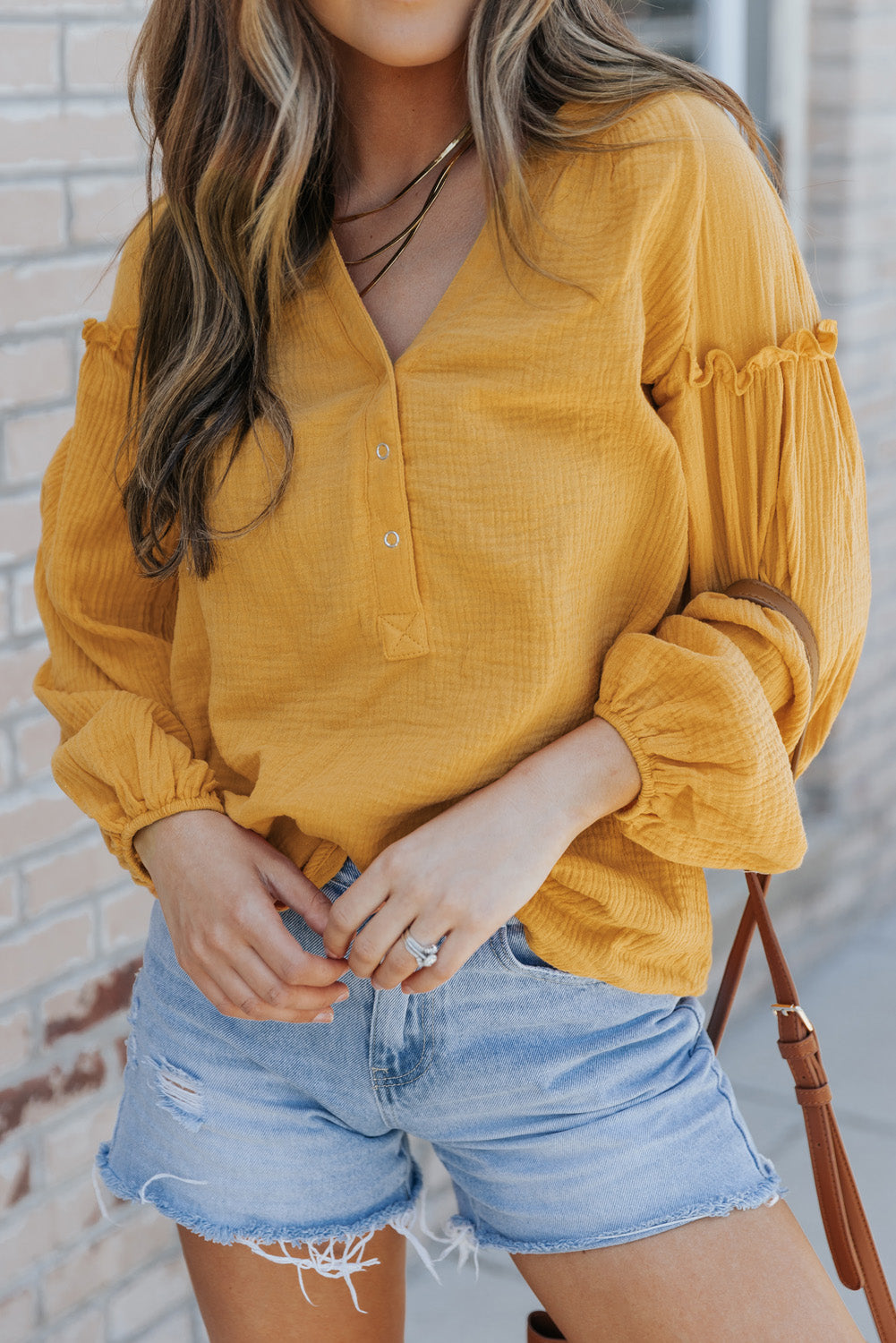 A stylish green casual top featuring balloon sleeves, a split neckline, and snap button closures, perfect for a chic and comfortable look.