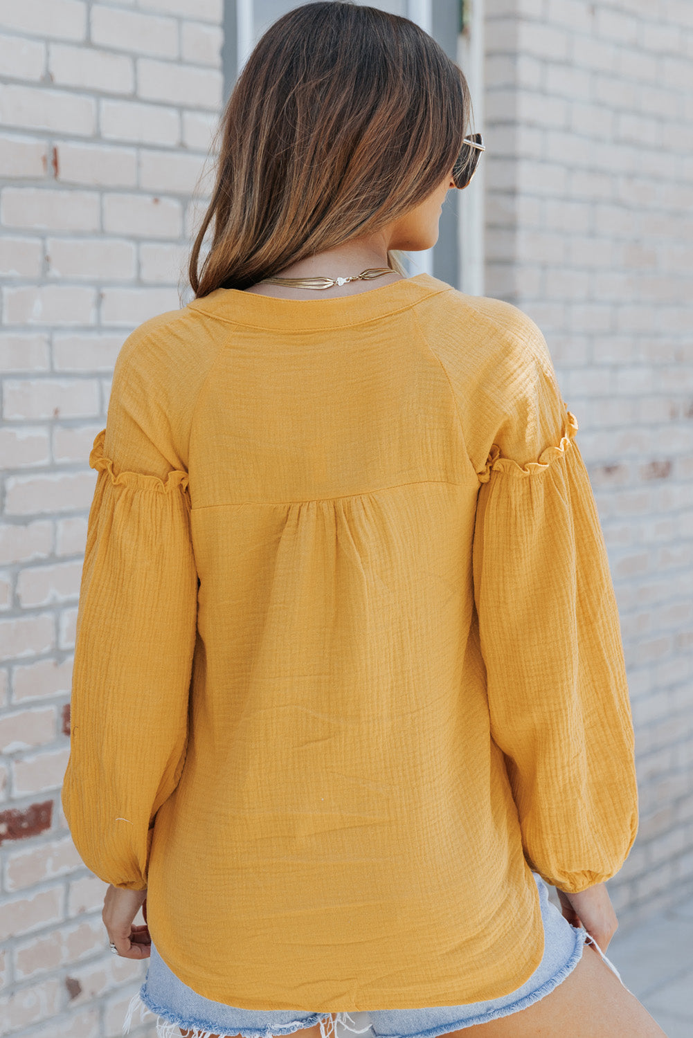 A stylish green casual top featuring balloon sleeves, a split neckline, and snap button closures, perfect for a chic and comfortable look.