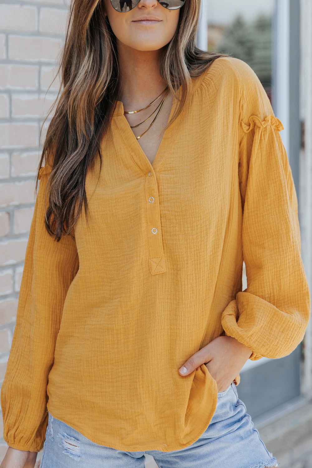 A stylish green casual top featuring balloon sleeves, a split neckline, and snap button closures, perfect for a chic and comfortable look.