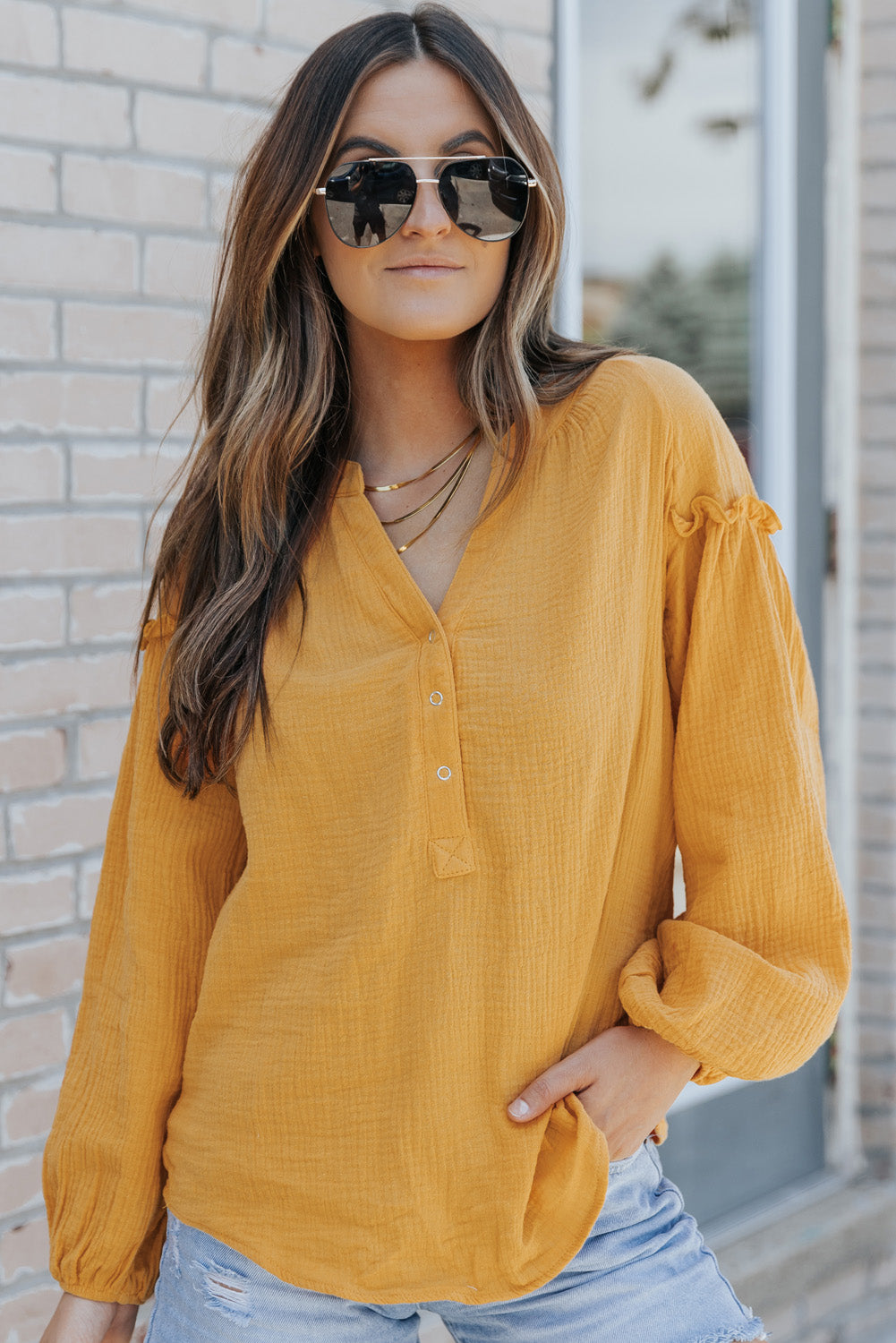 A stylish green casual top featuring balloon sleeves, a split neckline, and snap button closures, perfect for a chic and comfortable look.