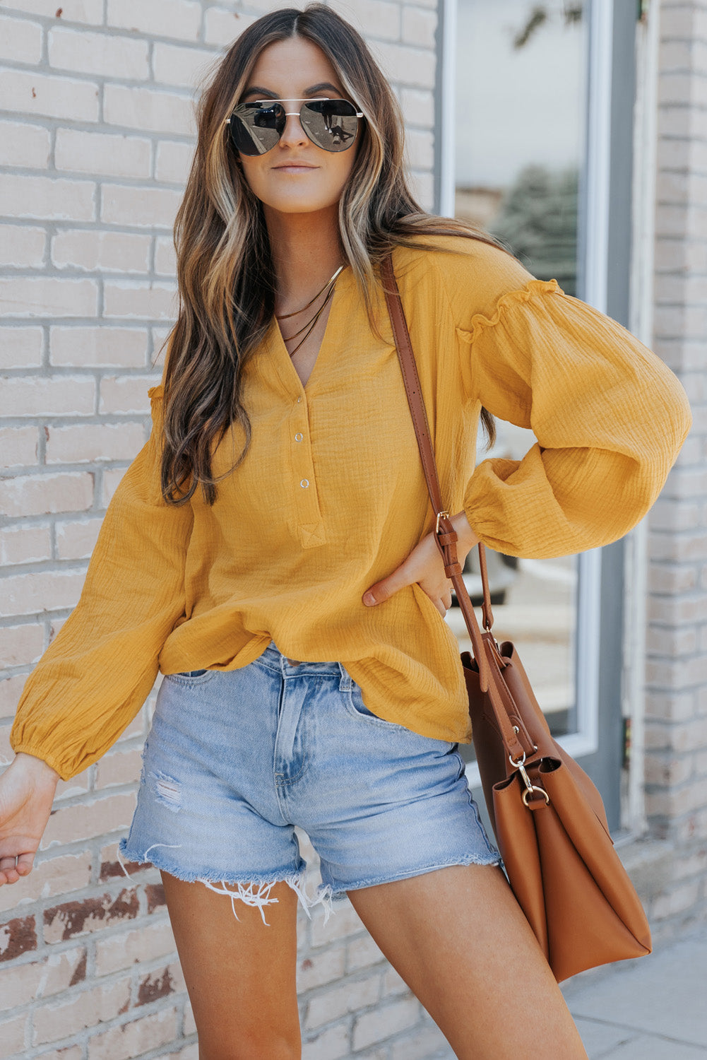 A stylish green casual top featuring balloon sleeves, a split neckline, and snap button closures, perfect for a chic and comfortable look.