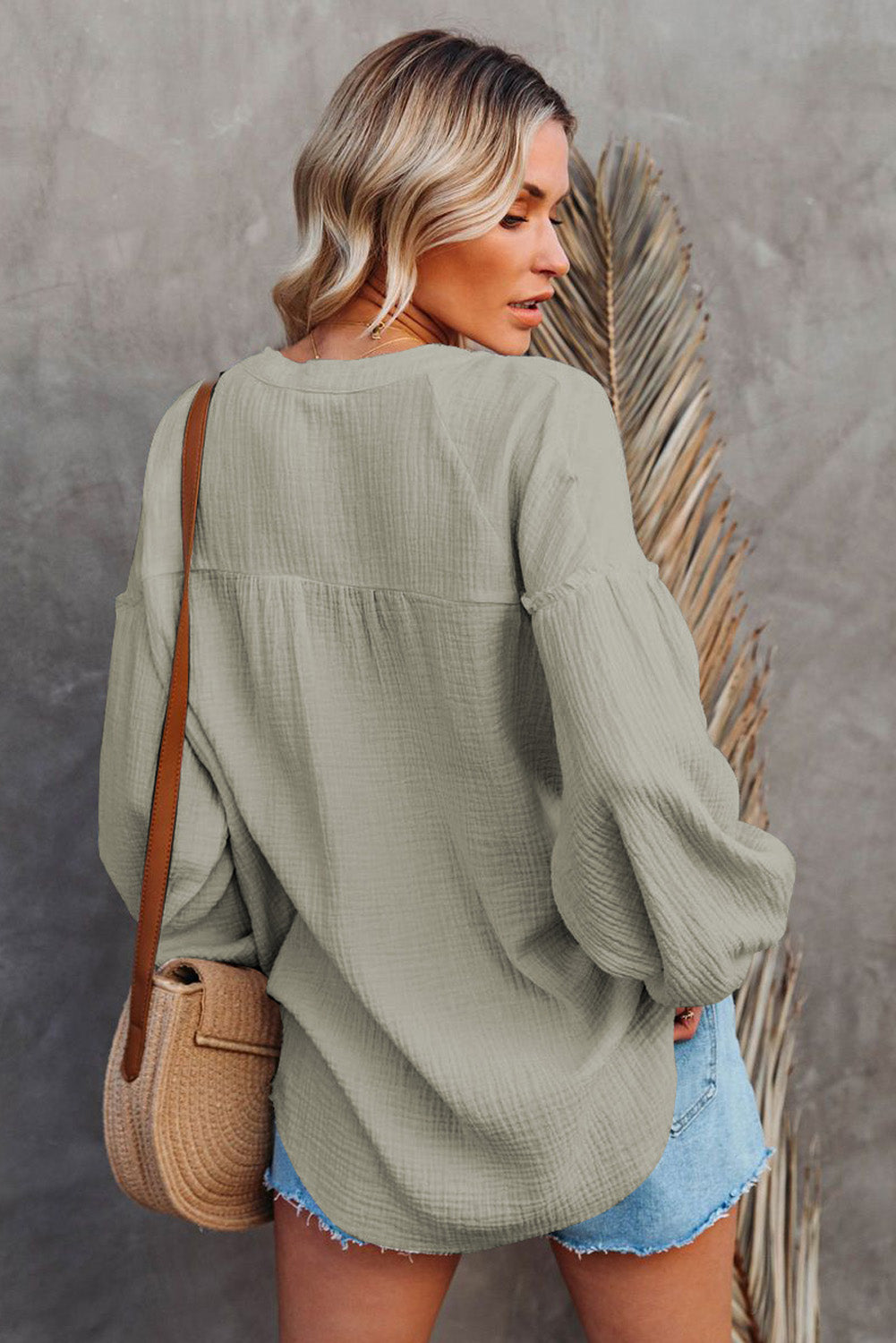 A stylish green casual top featuring balloon sleeves, a split neckline, and snap button closures, perfect for a chic and comfortable look.