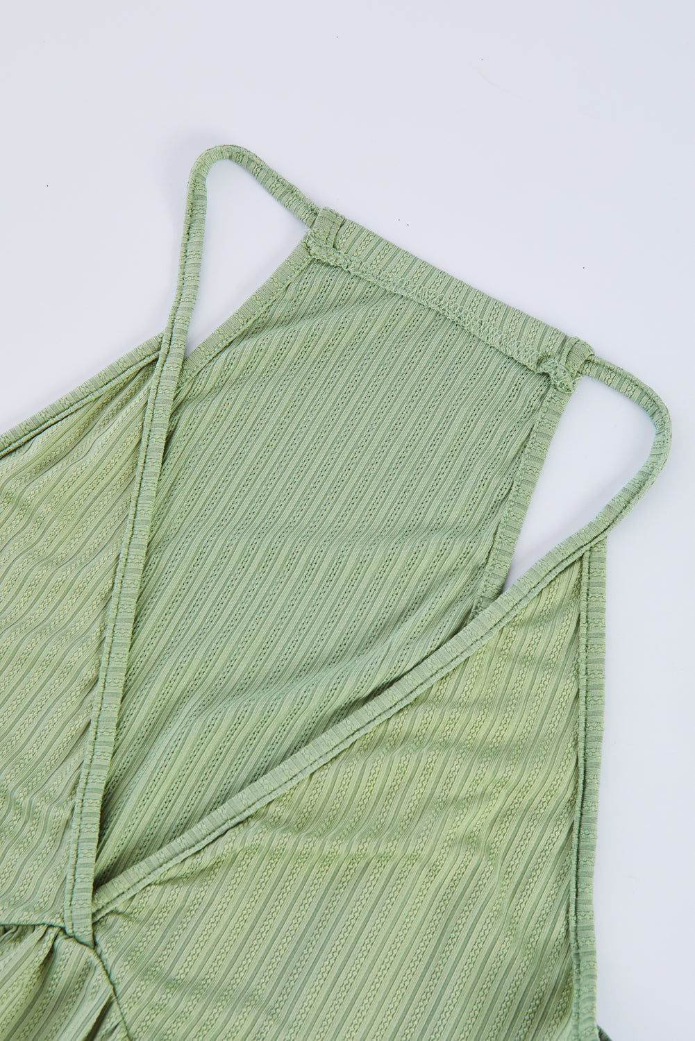 A stylish green deep V neckline ribbed babydoll tank top, perfect for summer wear, showcasing its lightweight knit material and flattering design.