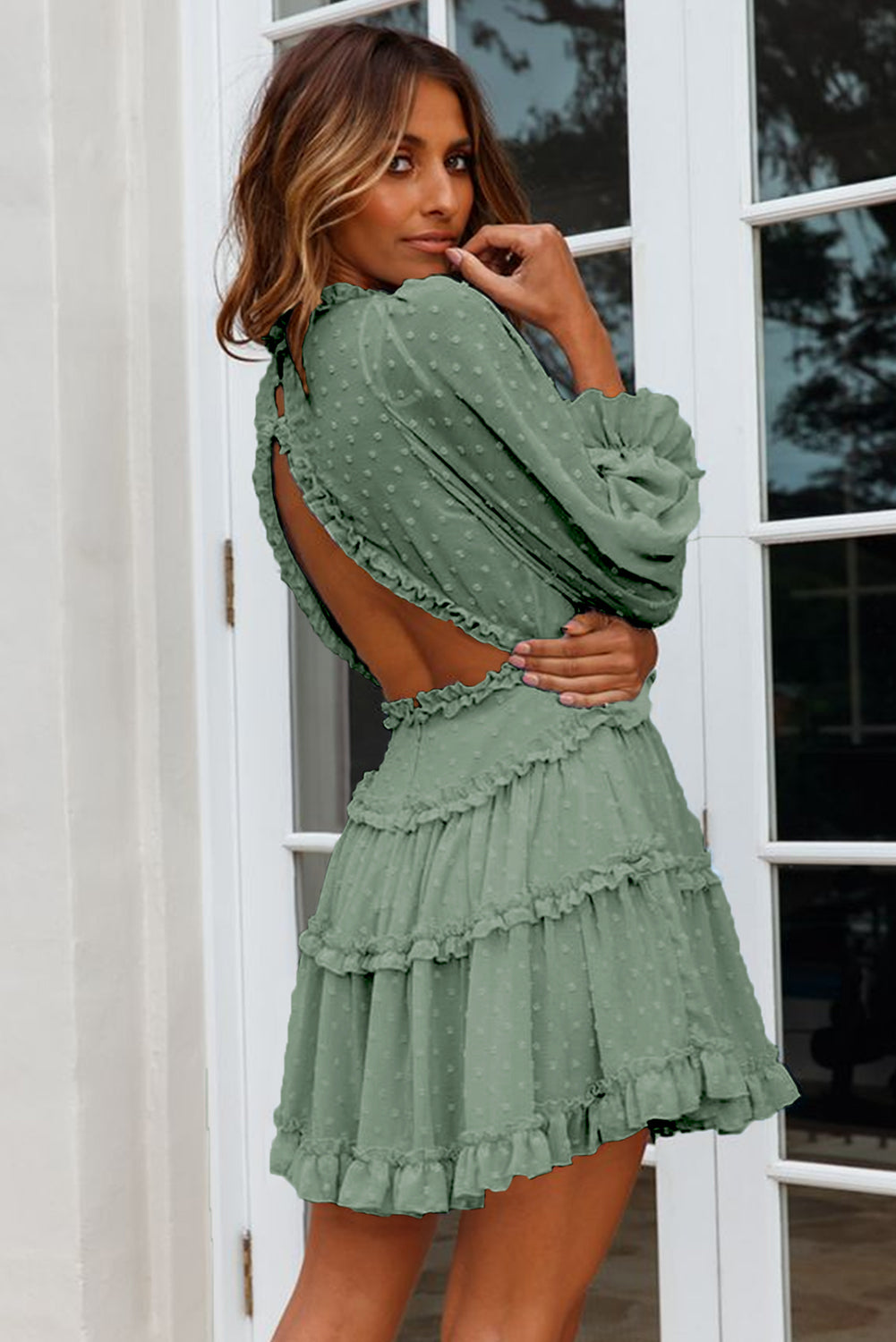 A stylish green mini dress featuring layered ruffles, puff sleeves, and an open back design, made from Swiss dot fabric.