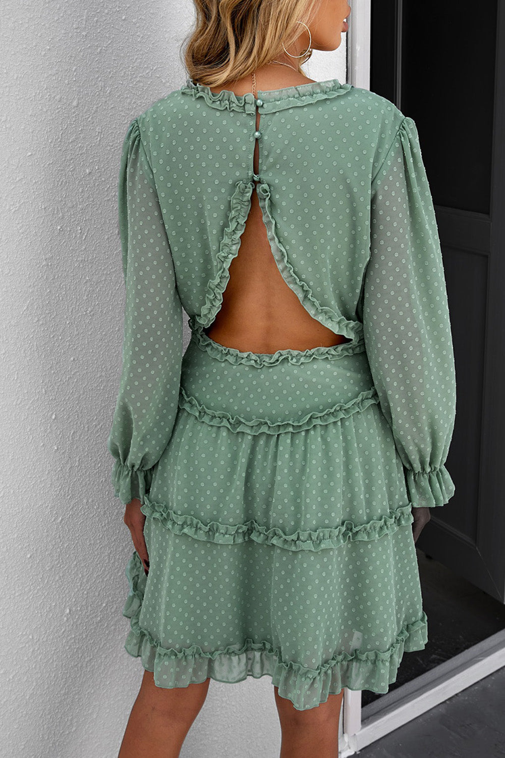 A stylish green mini dress featuring layered ruffles, puff sleeves, and an open back design, made from Swiss dot fabric.