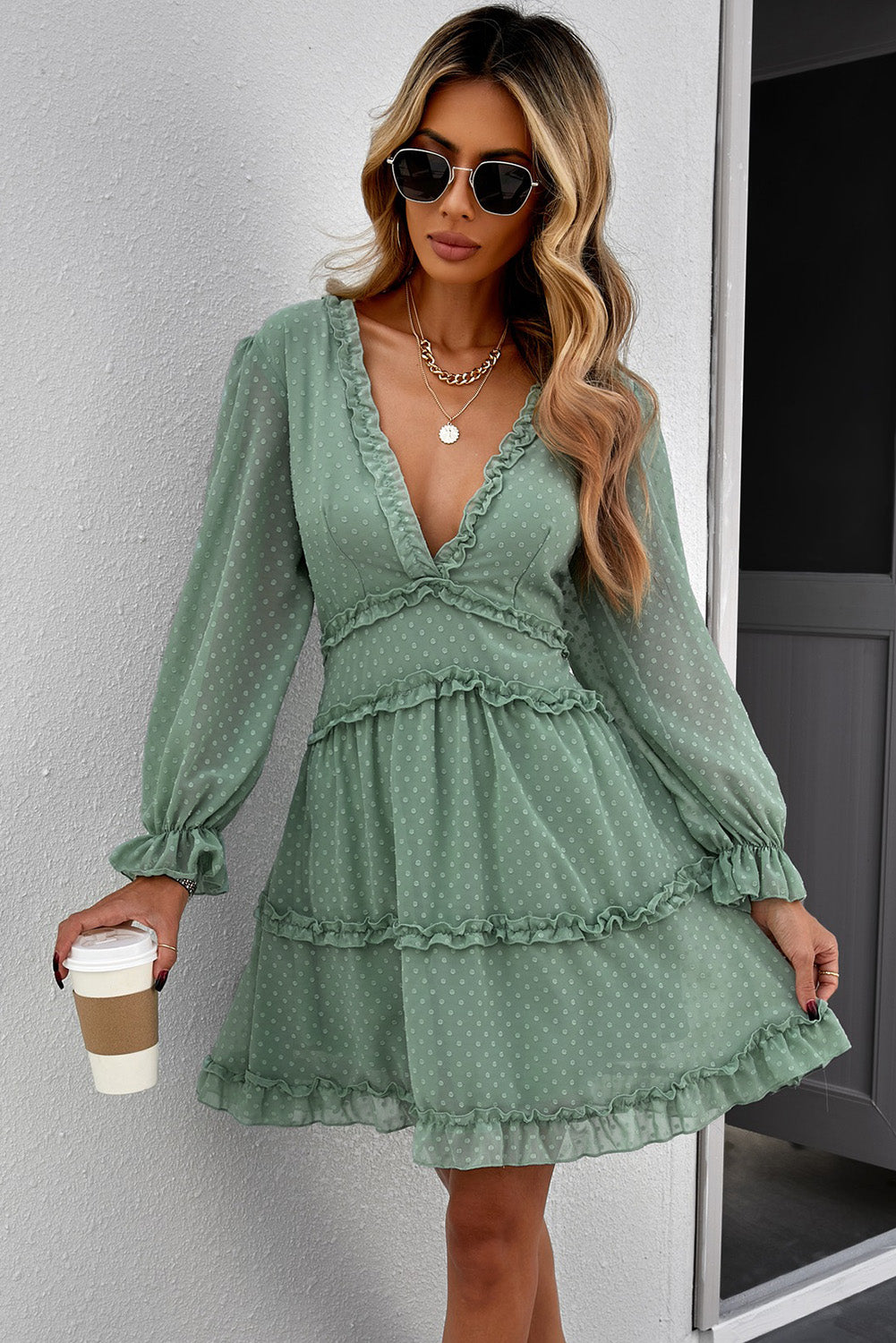 A stylish green mini dress featuring layered ruffles, puff sleeves, and an open back design, made from Swiss dot fabric.