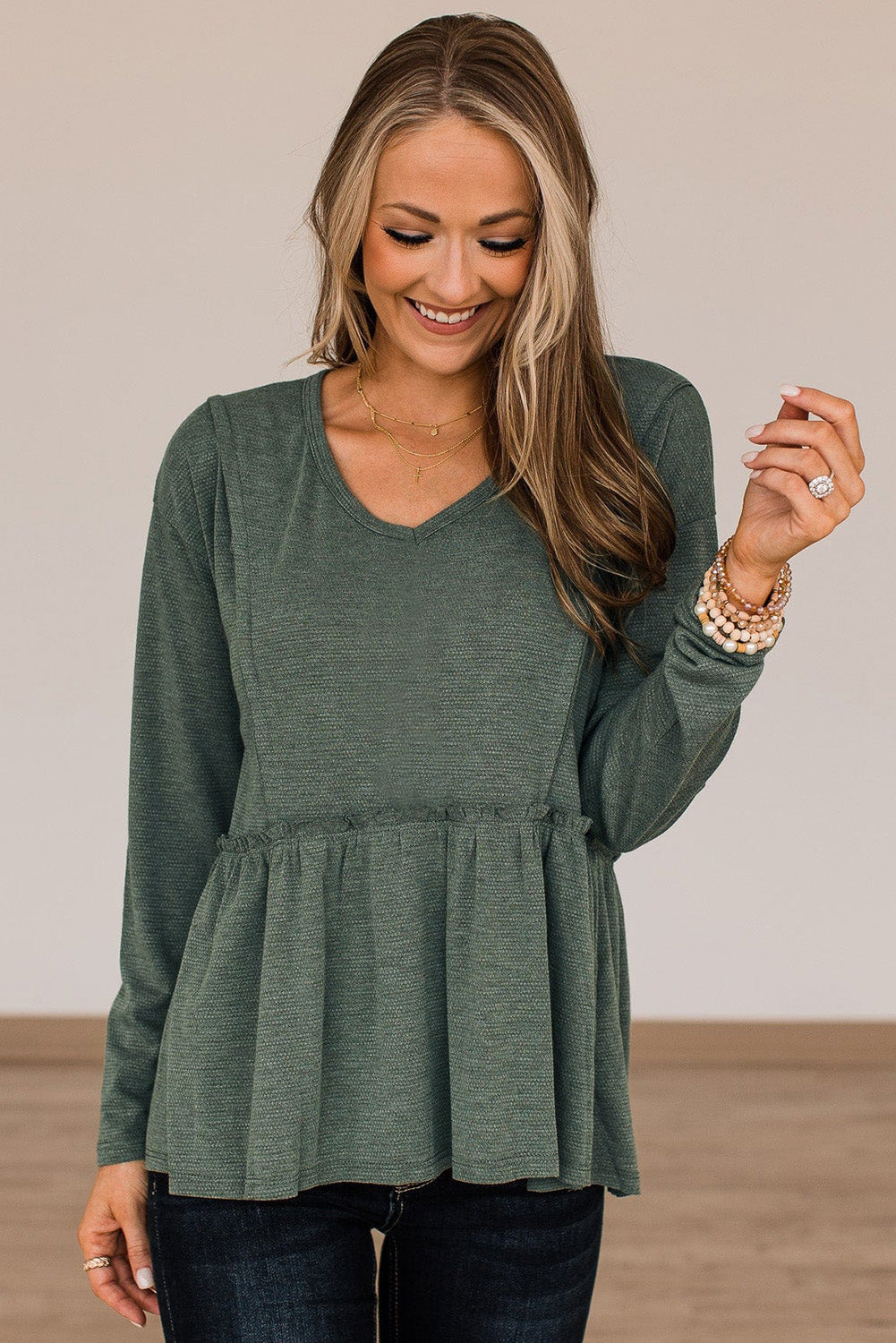 A stylish green long sleeve peplum top featuring outseam details and a ruffle trimmed waistline, perfect for casual and chic outfits.