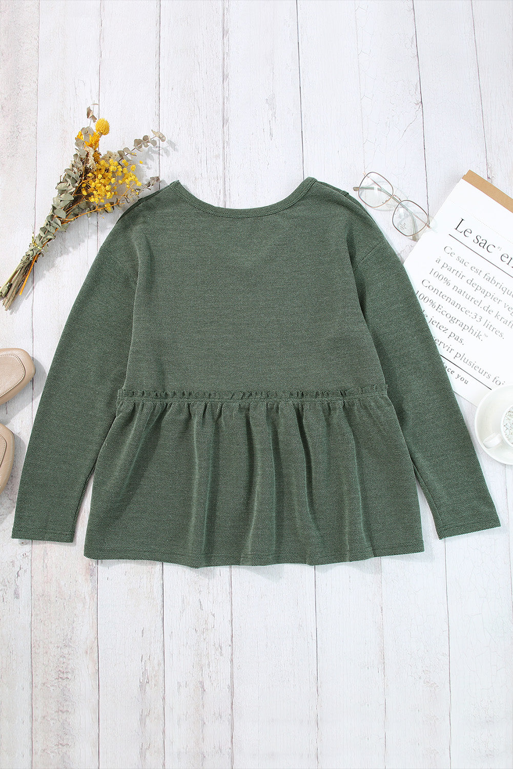 A stylish green long sleeve peplum top featuring outseam details and a ruffle trimmed waistline, perfect for casual and chic outfits.