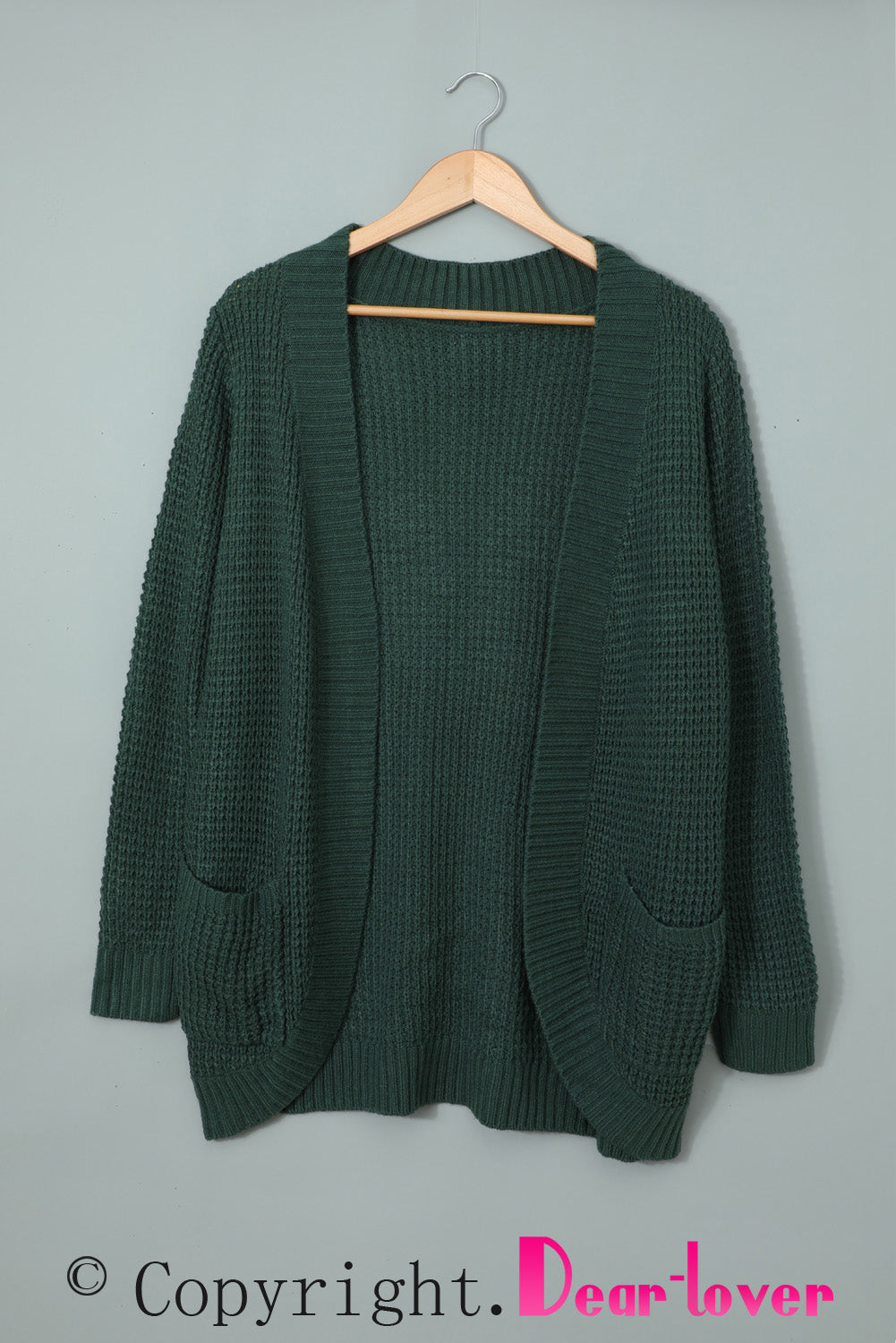 A stylish green pocket knitted solid color cardigan with a fuzzy texture and arc-shaped hem design, perfect for casual wear.