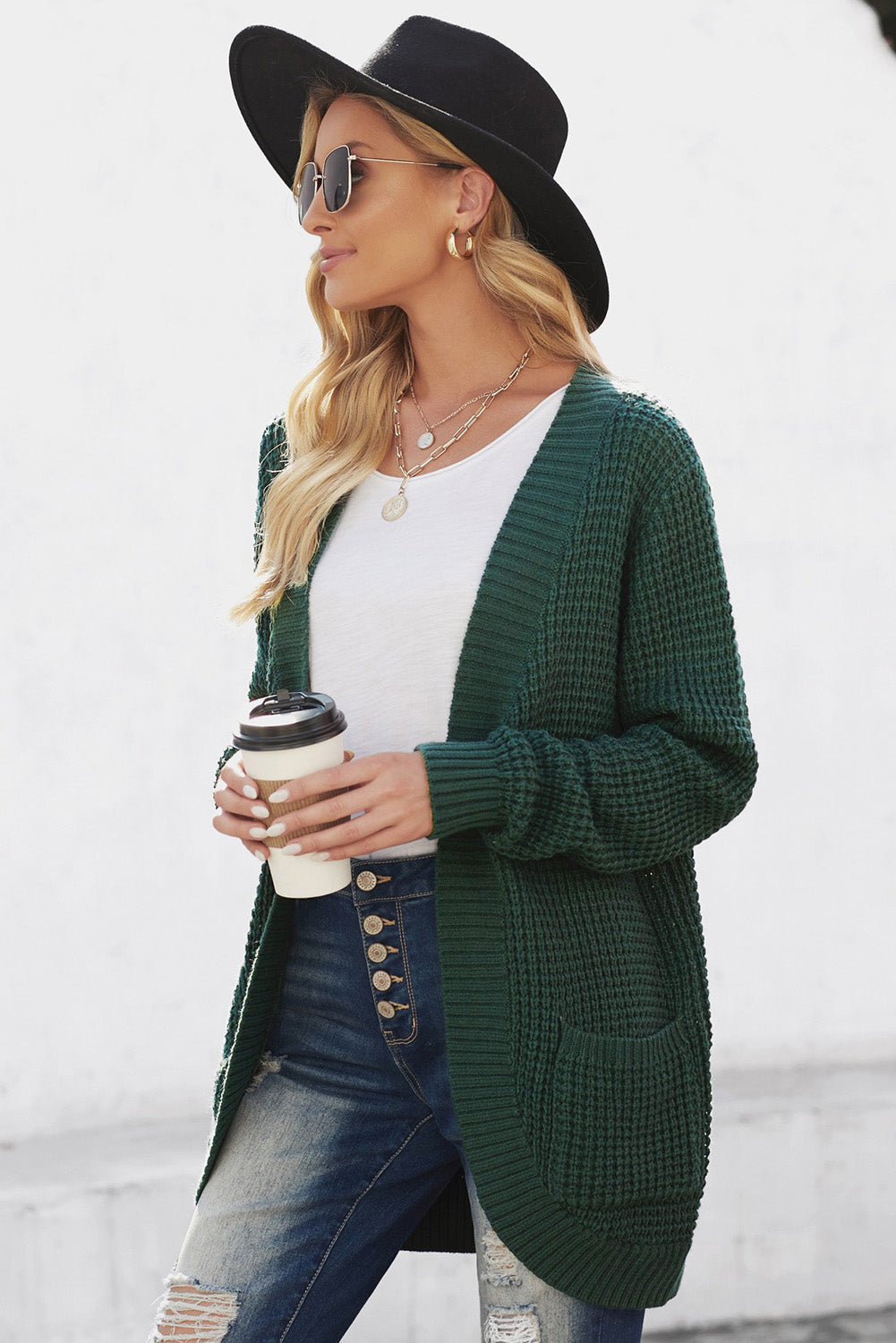 A stylish green pocket knitted solid color cardigan with a fuzzy texture and arc-shaped hem design, perfect for casual wear.